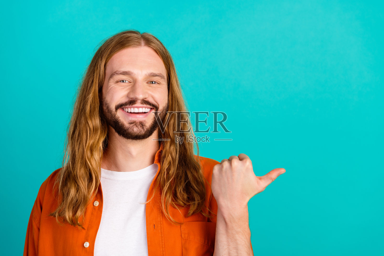 一个穿着橙色衬衫的开朗小伙子的肖像，在海蓝宝石的背景上向顾客提出了很好的建议照片摄影图片