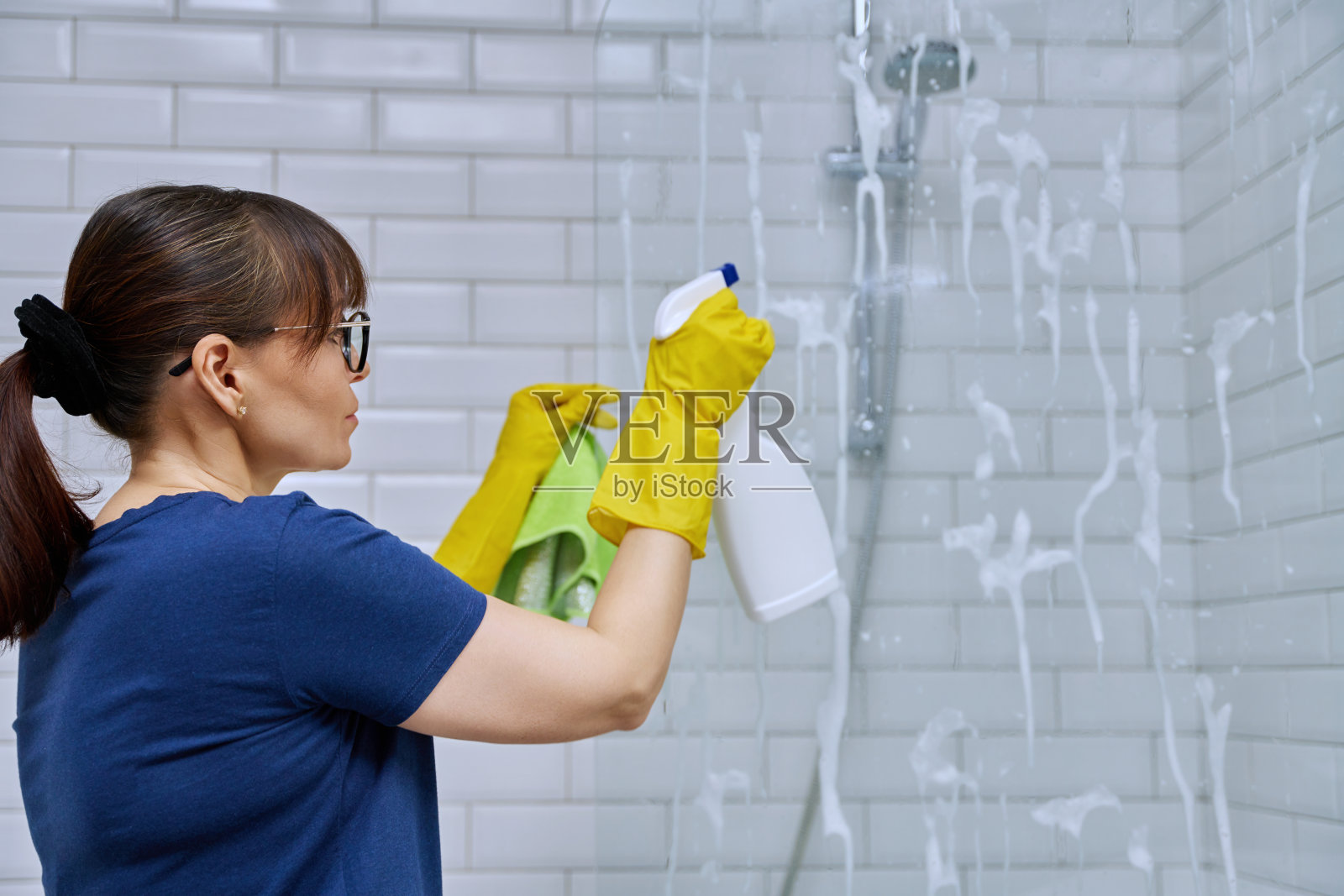 妇女打扫浴室，在淋浴间清洗玻璃照片摄影图片