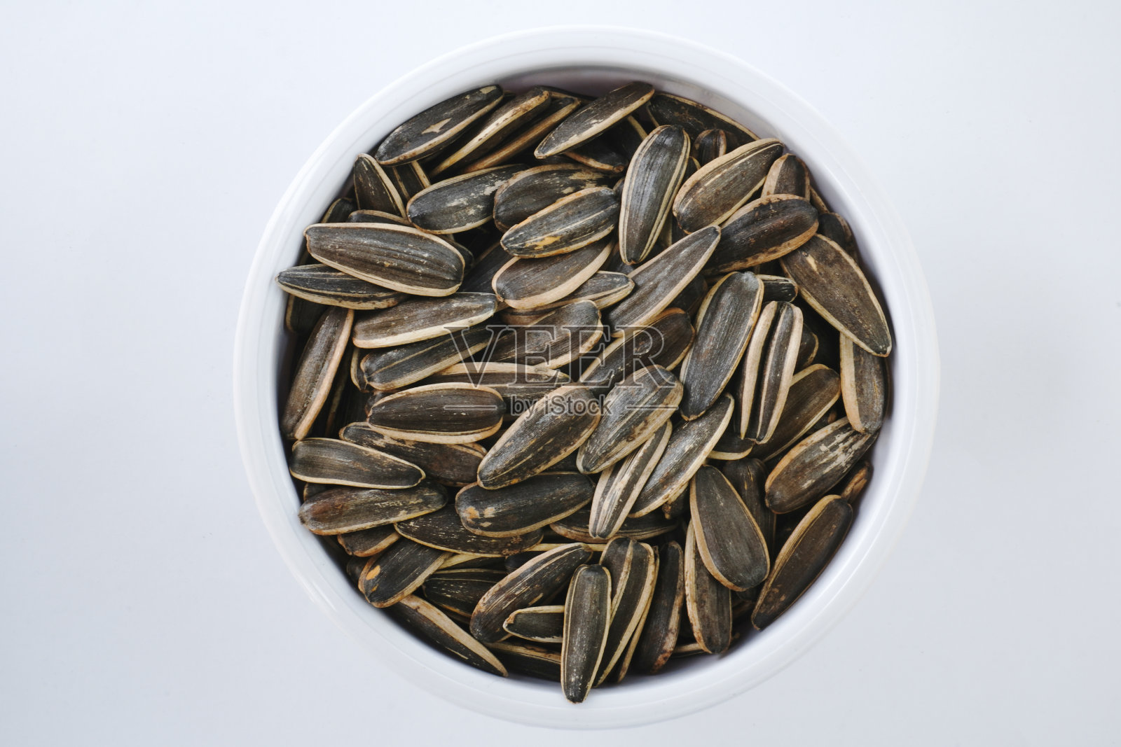 葵花籽放在白色的碗里，孤立在白色的背景上照片摄影图片