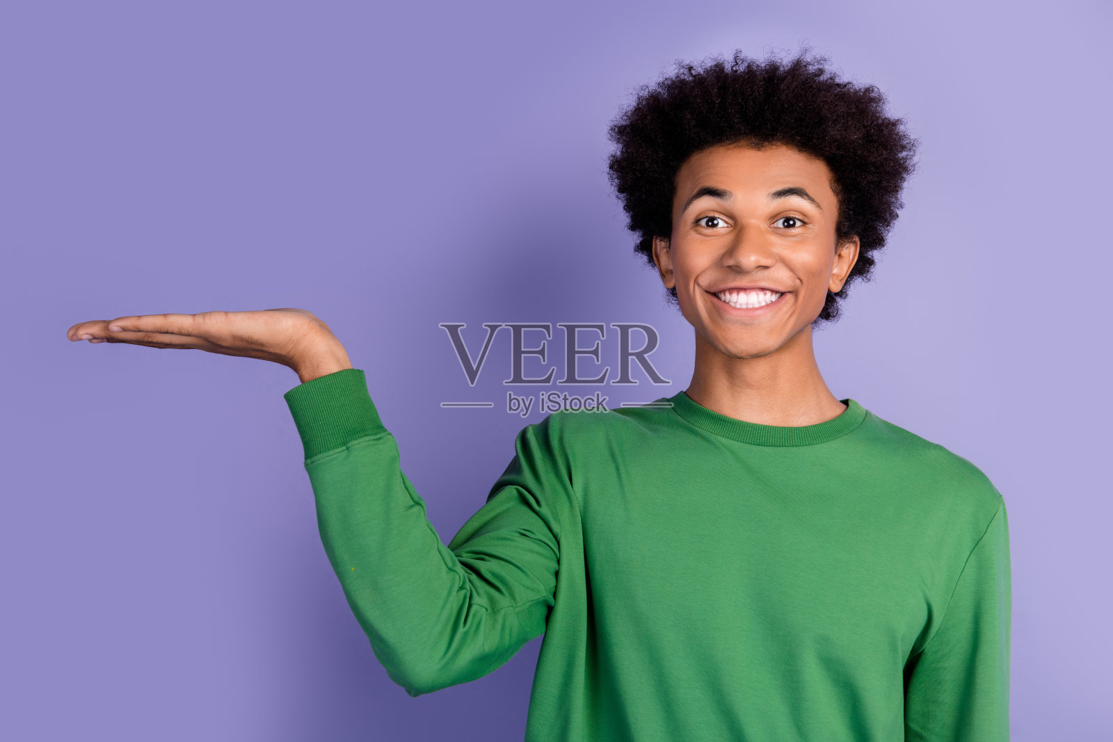 照片中心情愉快的男子穿着绿色毛衣，露出手臂空空荡荡的孤立的紫色背景照片摄影图片