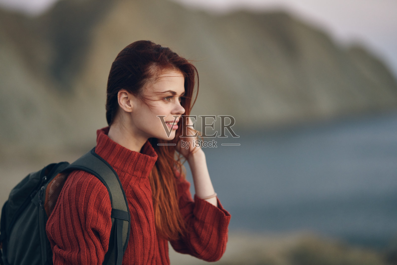 漂亮的女人穿着毛衣，背着背包，大海，山脉，自然，新鲜的空气照片摄影图片