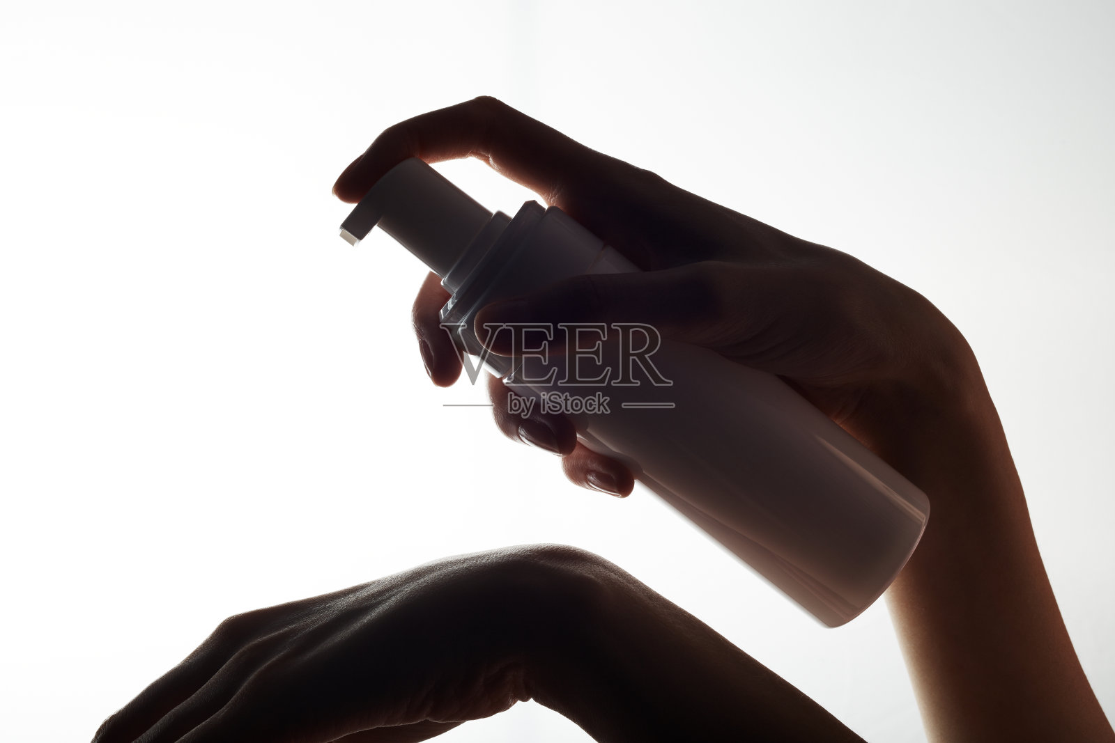 在白色背景上，一个女人手里拿着一个保湿霜管和分配器的白色模型特写。一名妇女在她的手上使用一根管子。照片摄影图片