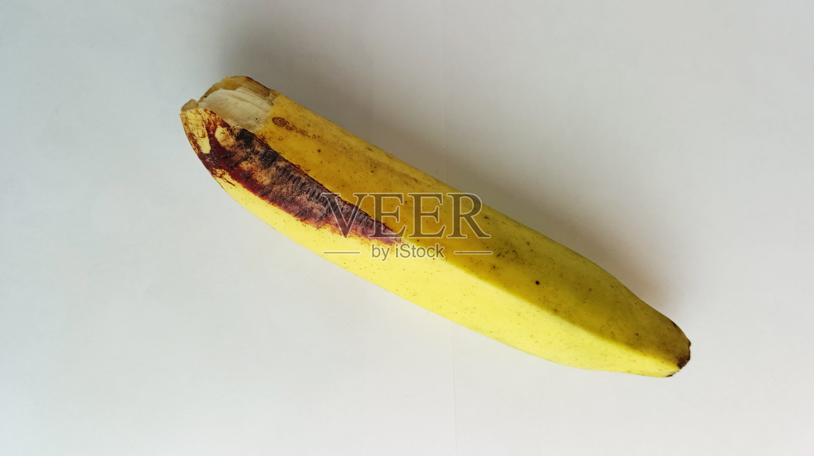 白色背景上有棕黑色斑点的黄色香蕉照片摄影图片