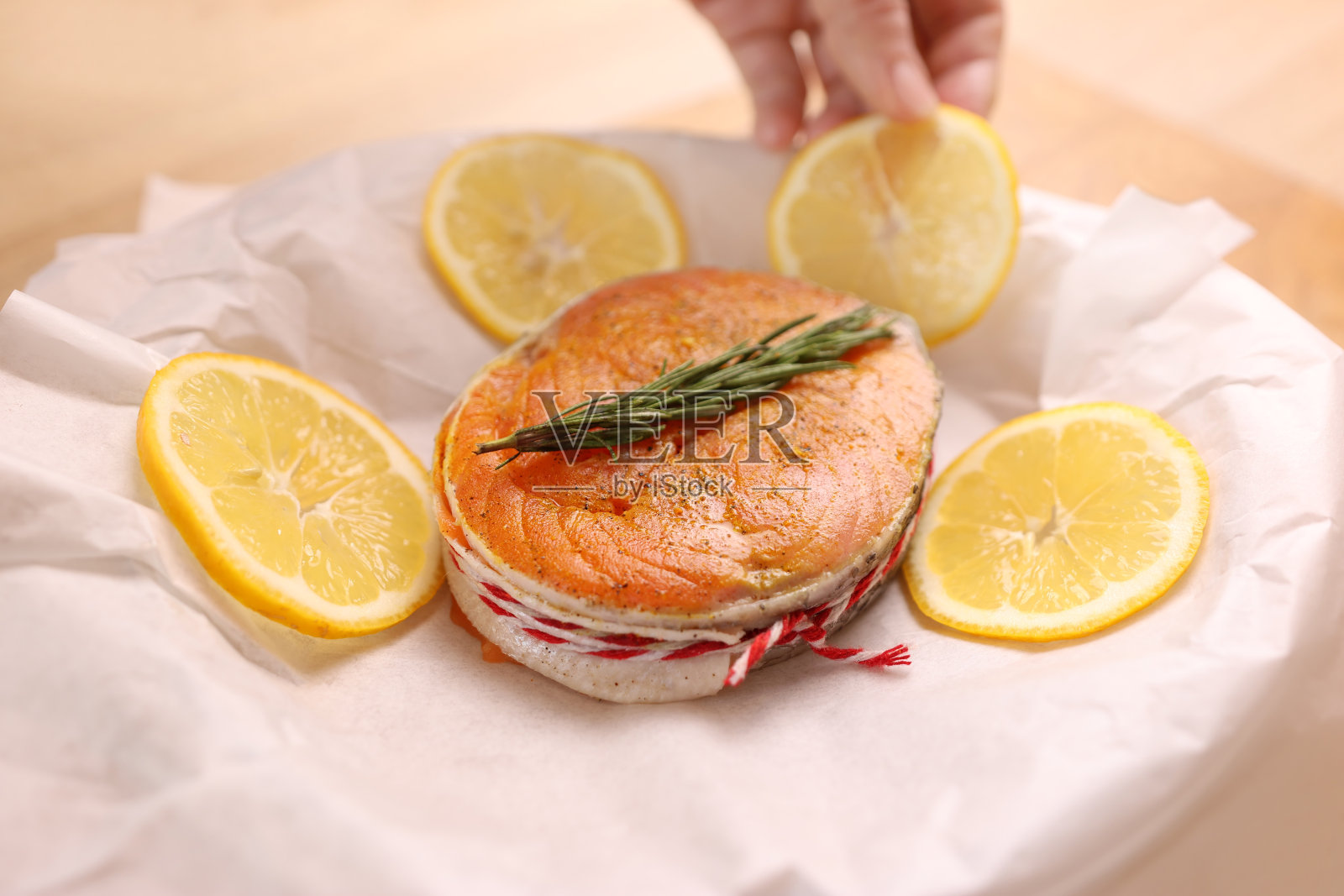 烤的时候，把一片三文鱼放在盘子里，放在羊皮纸上，然后加入柠檬照片摄影图片