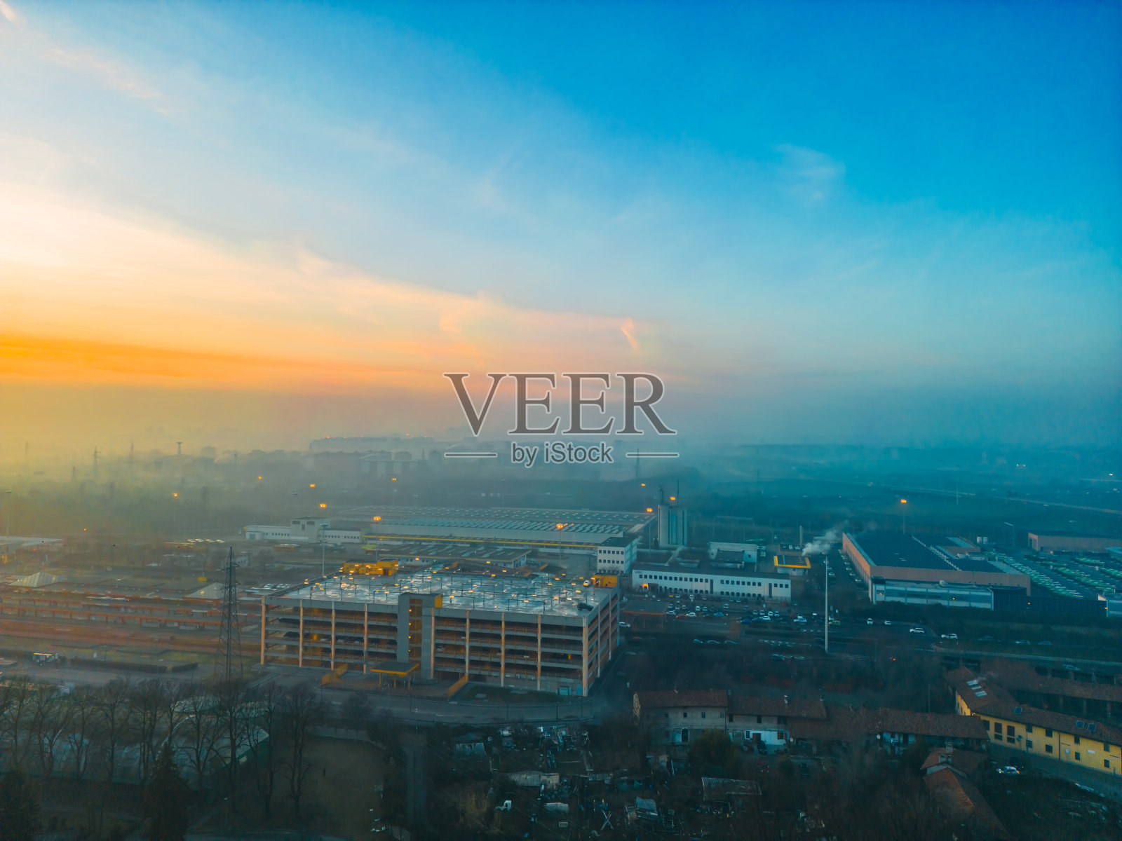 2024年2月4日，意大利米兰伦巴第，从无人机上拍摄的雾蒙蒙的日出与圣多纳托米兰天际线照片摄影图片