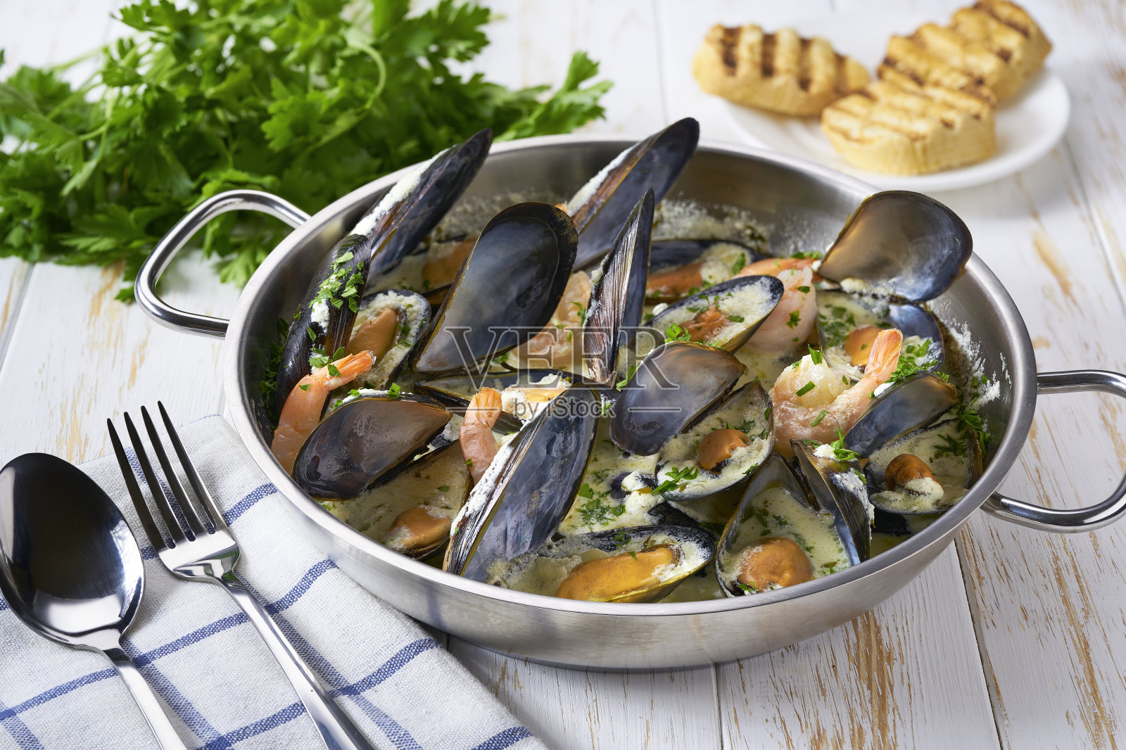 用金属锅煮白汁的美味海鲜。照片摄影图片