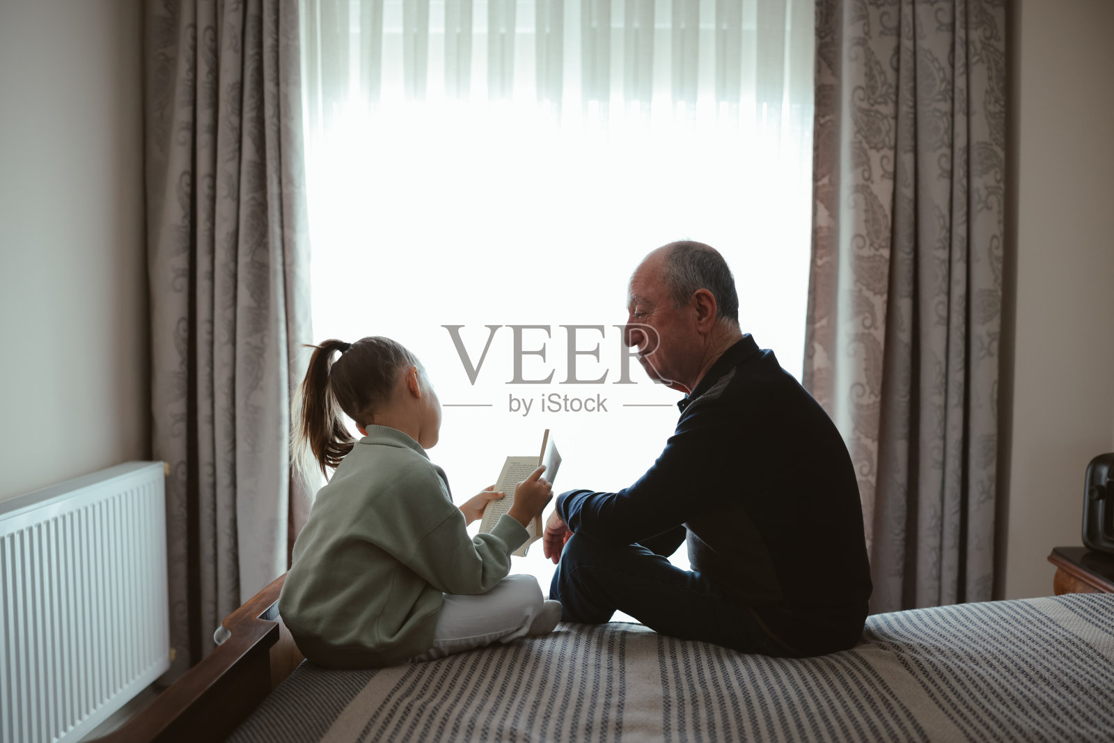 开心的爷爷和孙女在家里一起读书照片摄影图片