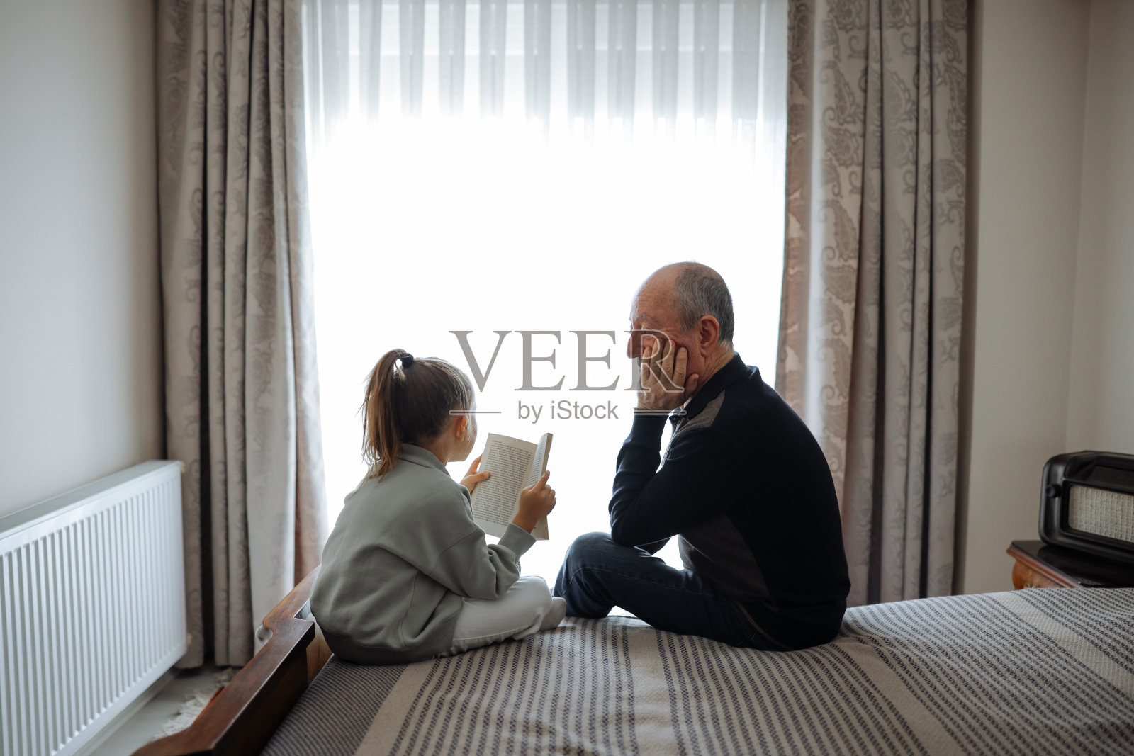 开心的爷爷和孙女在家里一起读书照片摄影图片