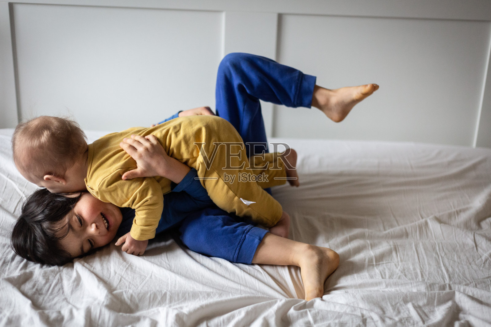 两个快乐的孩子在父母的床上互相拥抱的侧视图照片摄影图片