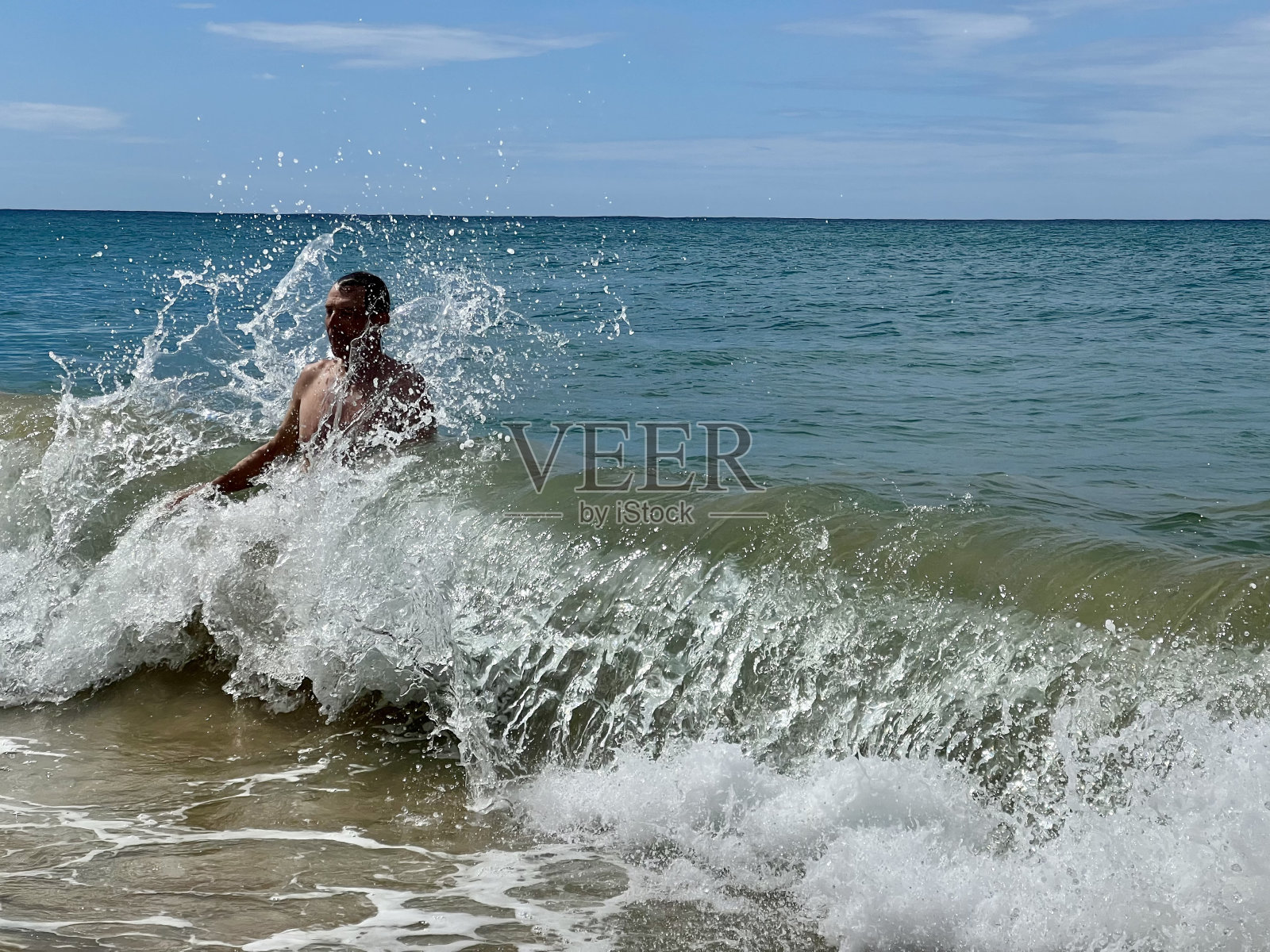 波多黎各，一名老人站在水里玩得很开心，周围的海浪正在拍打他照片摄影图片