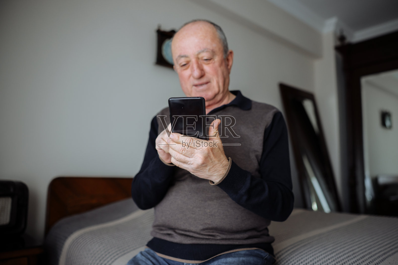 开朗的成熟男人在家里躺在床上玩手机照片摄影图片