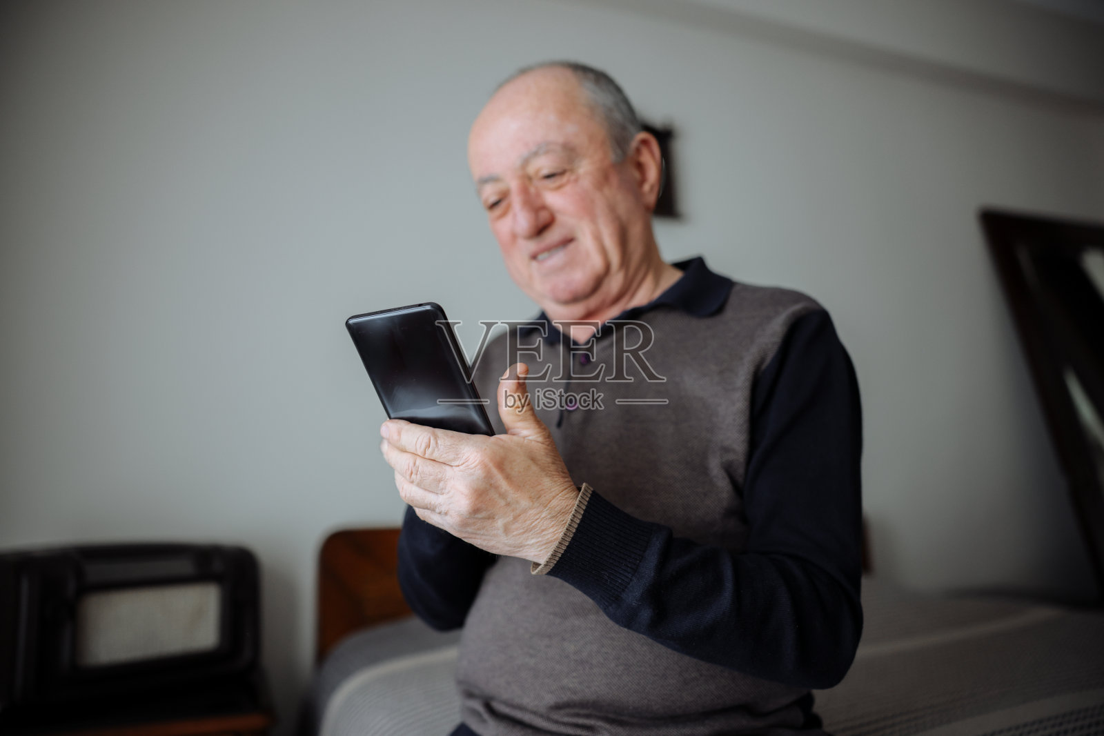 开朗的成熟男人在家里躺在床上玩手机照片摄影图片