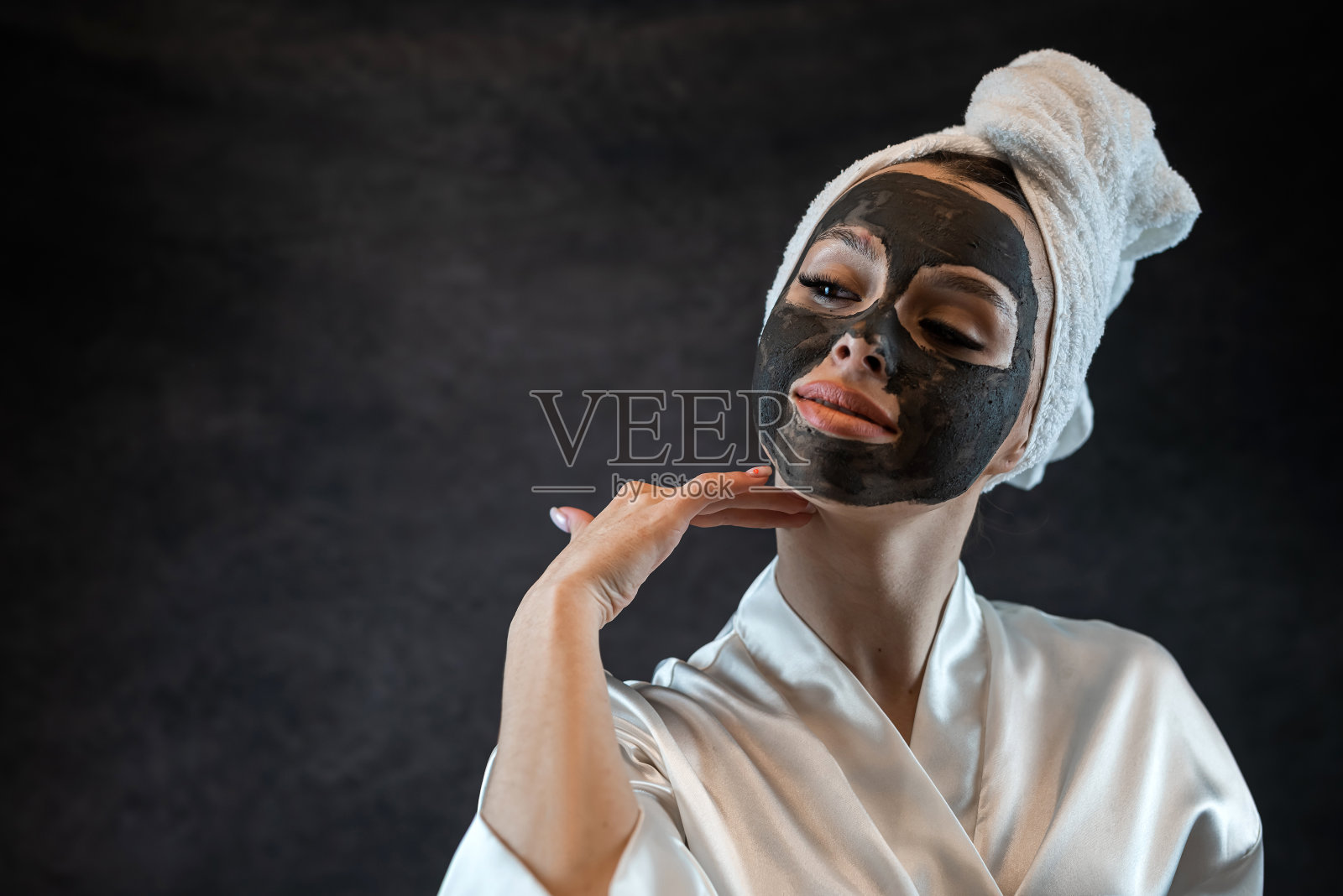 高加索妇女在脸上涂上白色毛巾和黑色粘土泥滋养面膜隔离上黑色照片摄影图片