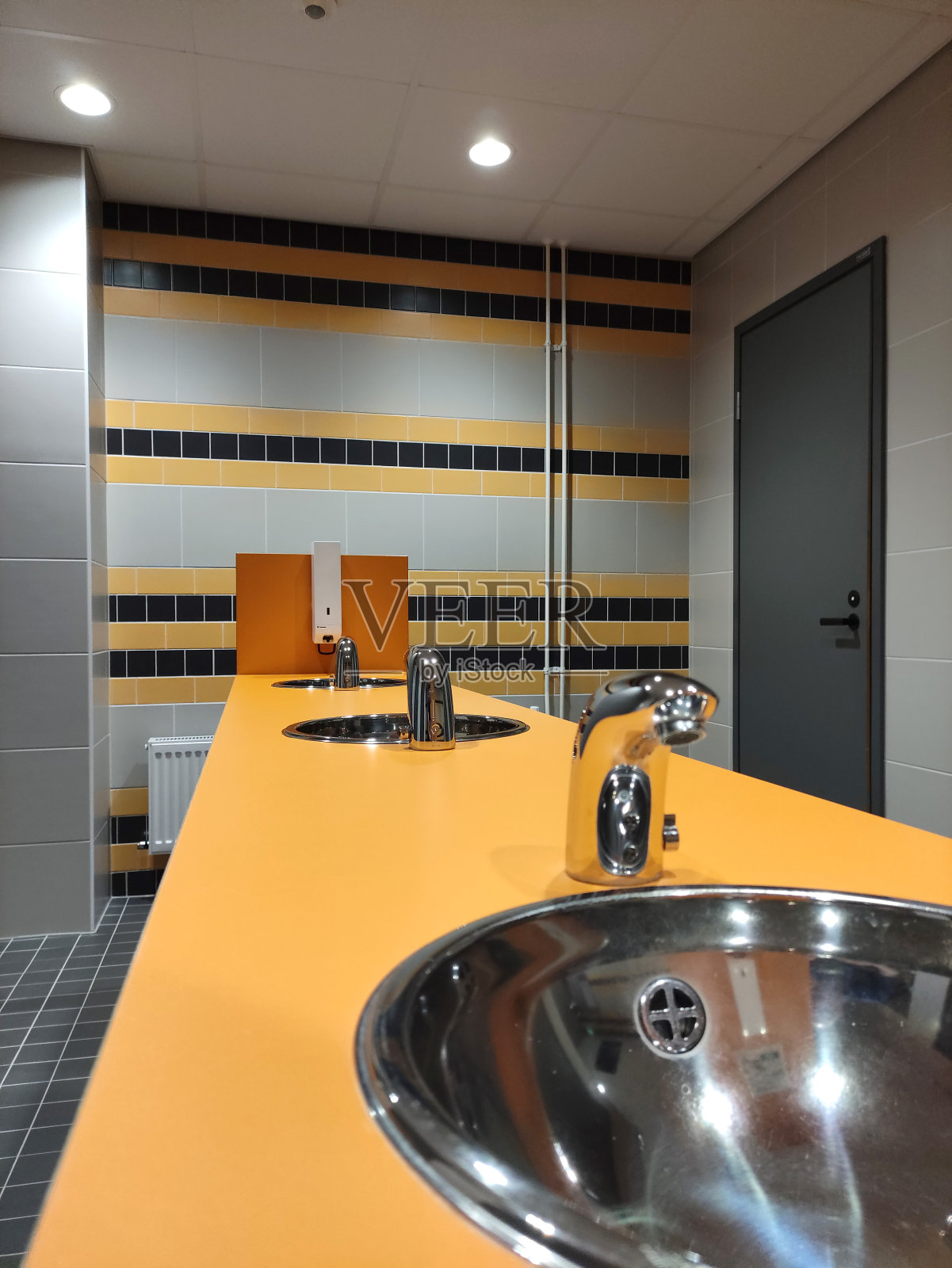 公共厕所的金属水槽和带光电池的水龙头，非接触式。照片摄影图片