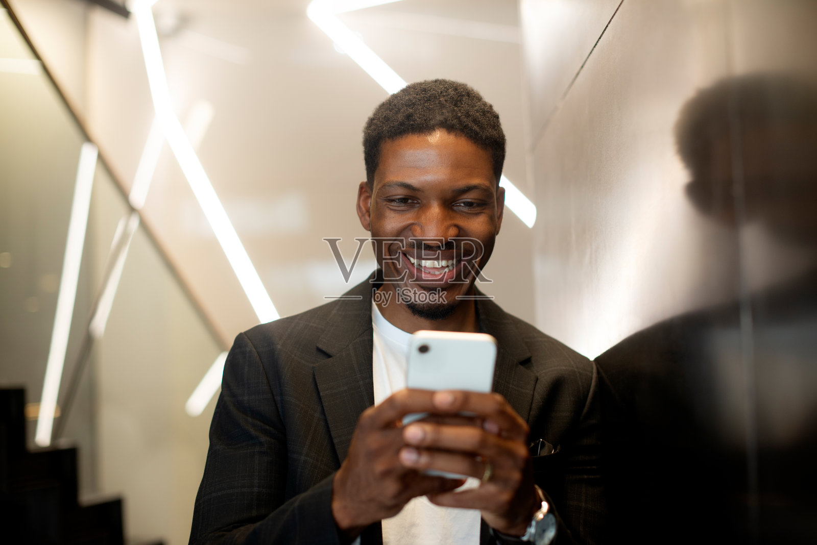 旅游，商务或快乐的黑人在酒店电话预订，预订或通知。智能手机、搜索引擎或男性创业者在电梯里使用在线入住应用、支付或服务评论照片摄影图片