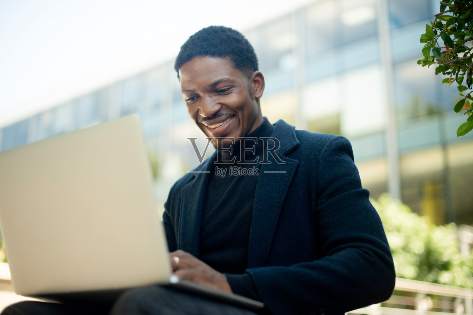 快乐，商务和黑人男子带着笔记本电脑在户外进行研究和远程工作在城市。非洲，商人和打字电子邮件通信在电脑上进行在线，联系和阅读信息照片摄影图片