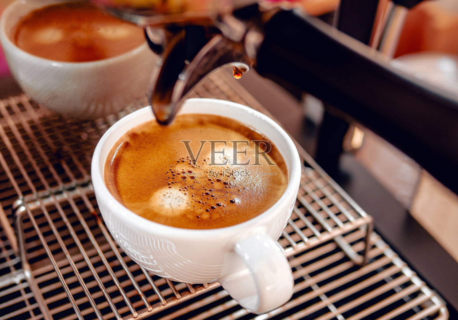 浓缩咖啡从咖啡机倒进咖啡杯的特写。专业咖啡冲泡，咖啡奶油照片摄影图片