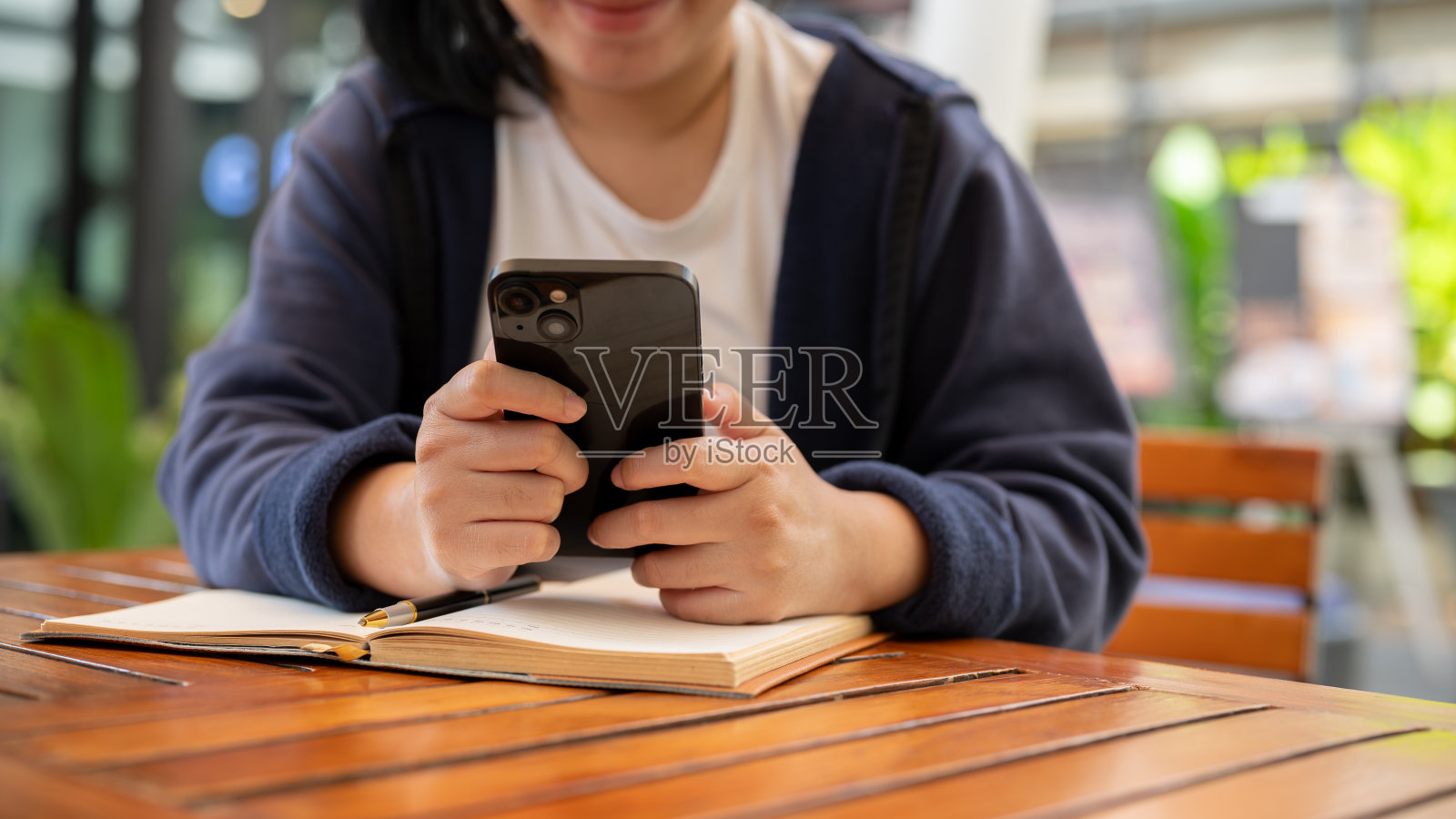 坐在咖啡馆里玩手机、阅读在线文章或回复信息的女性。照片摄影图片