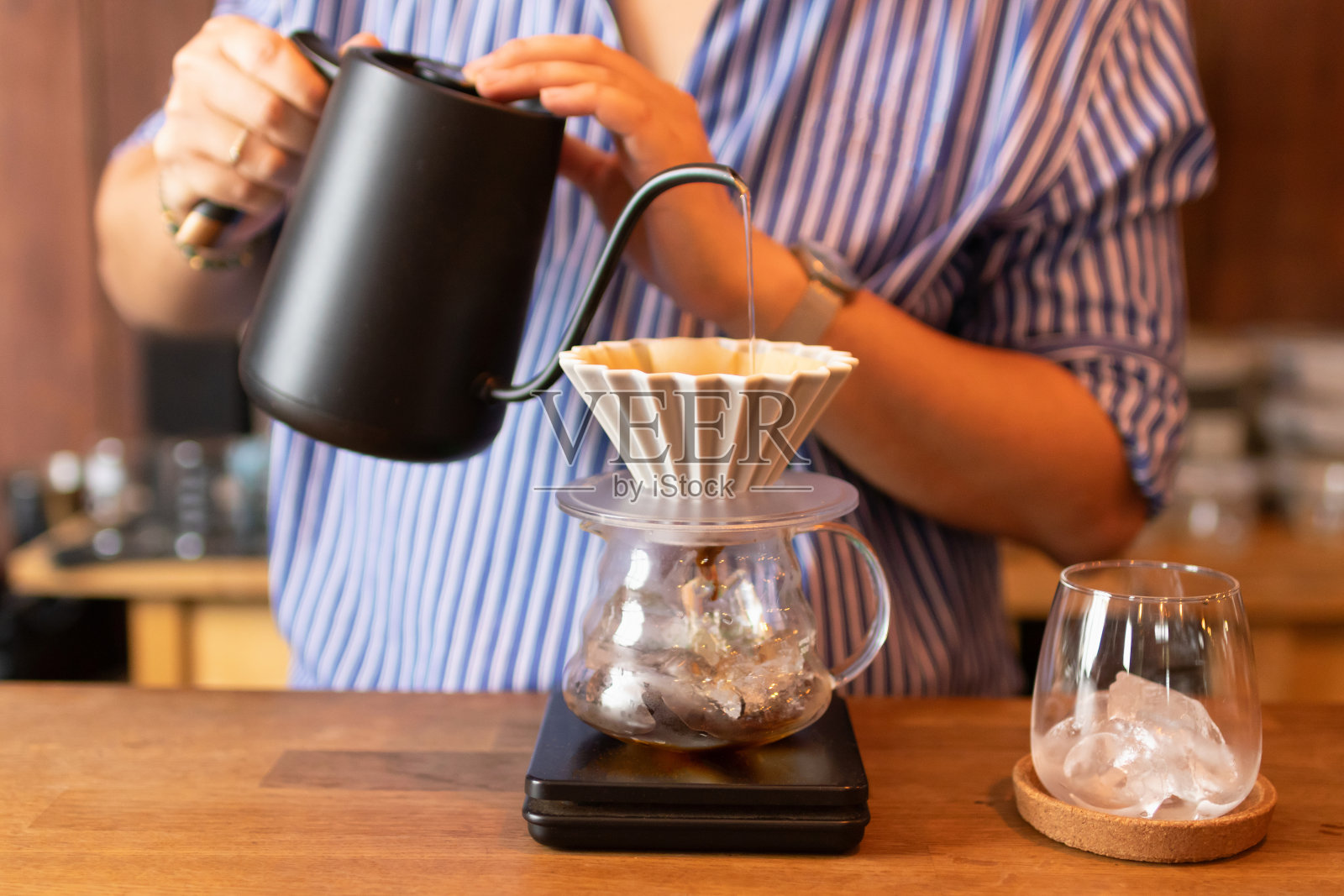 滴在冰上;咖啡师将热水倒在经过冰过滤的焙烤咖啡粉上。照片摄影图片