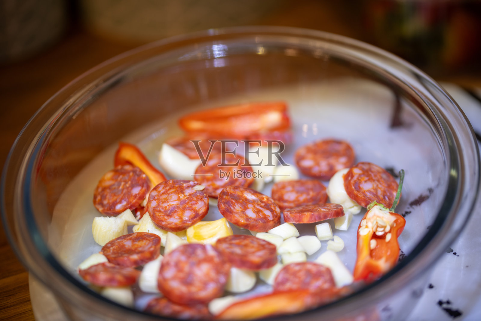 切成薄片的红辣椒辣香肠和大蒜片放在防玻璃的烤箱盘子里等待烘烤照片摄影图片