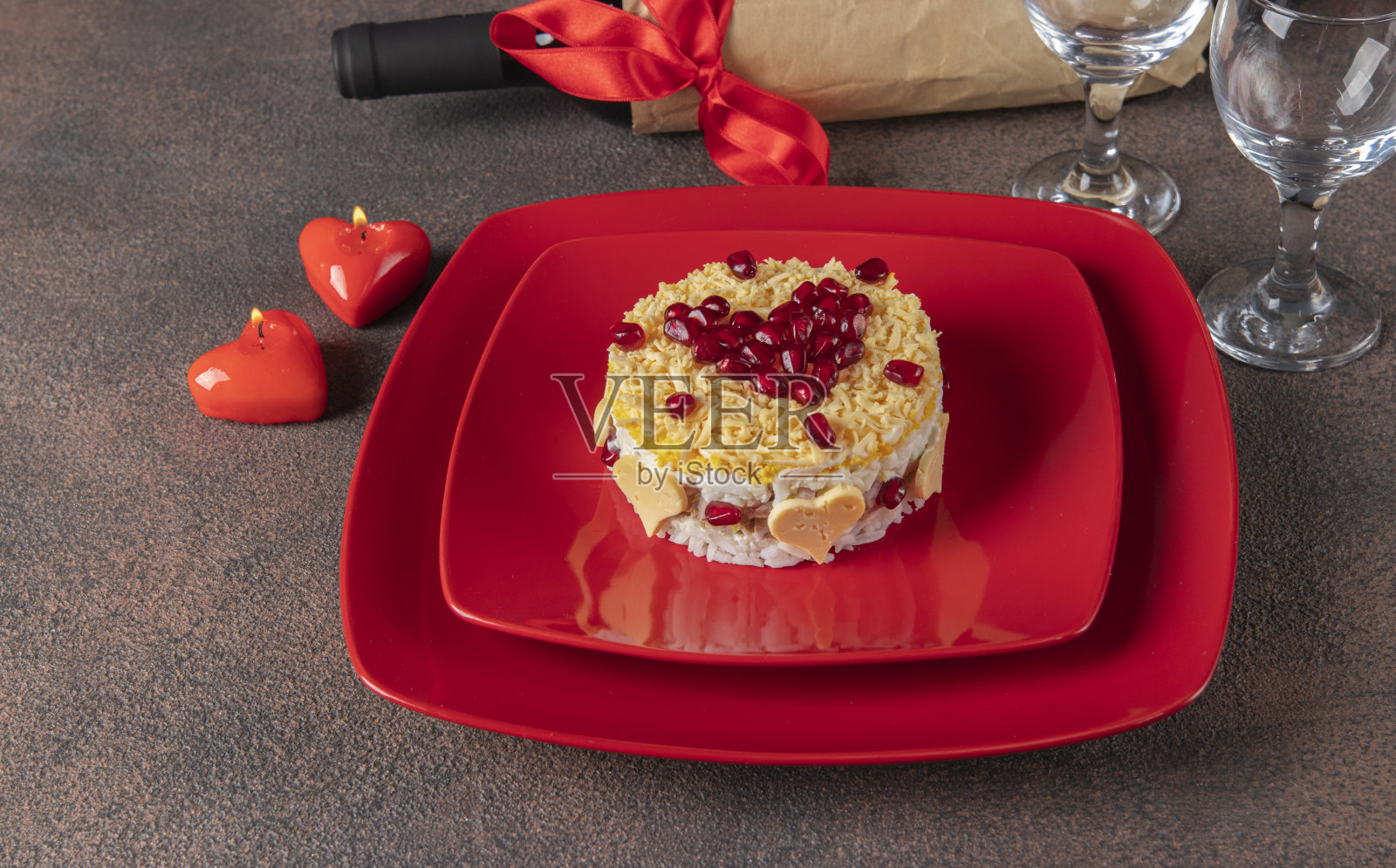 情人节的节日泡芙沙拉，有米饭、鸡肉、鸡蛋和奶酪，用红盘子里的心形石榴装饰照片摄影图片