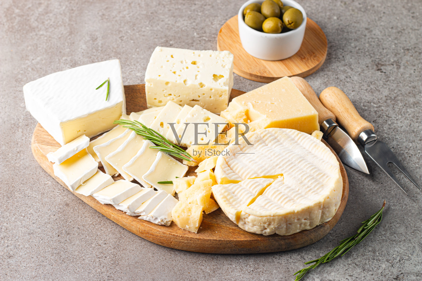木板上有各种奶酪和橄榄。布里干酪。乳酪。帕尔马干酪，菲达干酪，蓝纹奶酪。意大利奶酪，法国奶酪。照片摄影图片