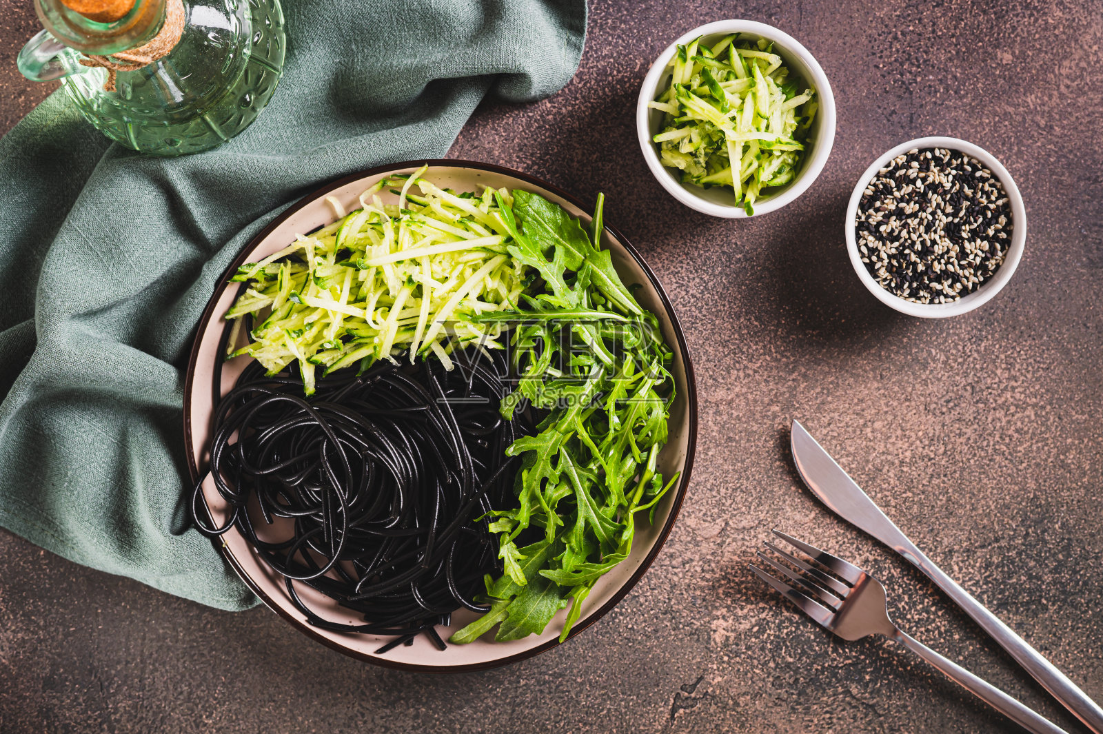 素菜黑色意大利面，黄瓜和芝麻菜叶子放在盘子上的桌面视图照片摄影图片