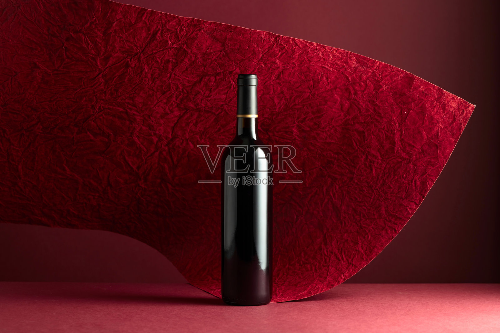 一瓶红色背景的红酒。照片摄影图片