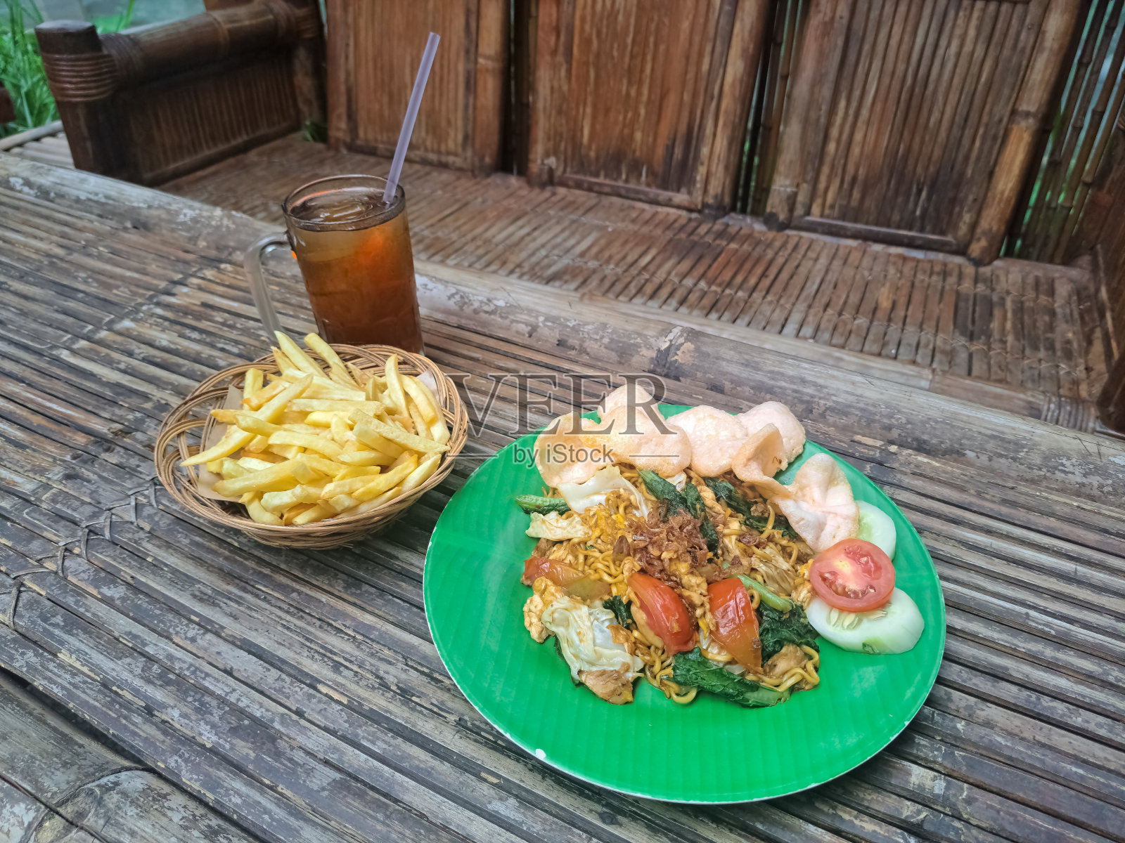 即食炒面或米糠炒面配炸薯条和冰鲜茶。Mi Goreng Instan Dengan Kentang Goreng Dan Minuman Es Teh Segar。食物和饮料菜单。照片摄影图片