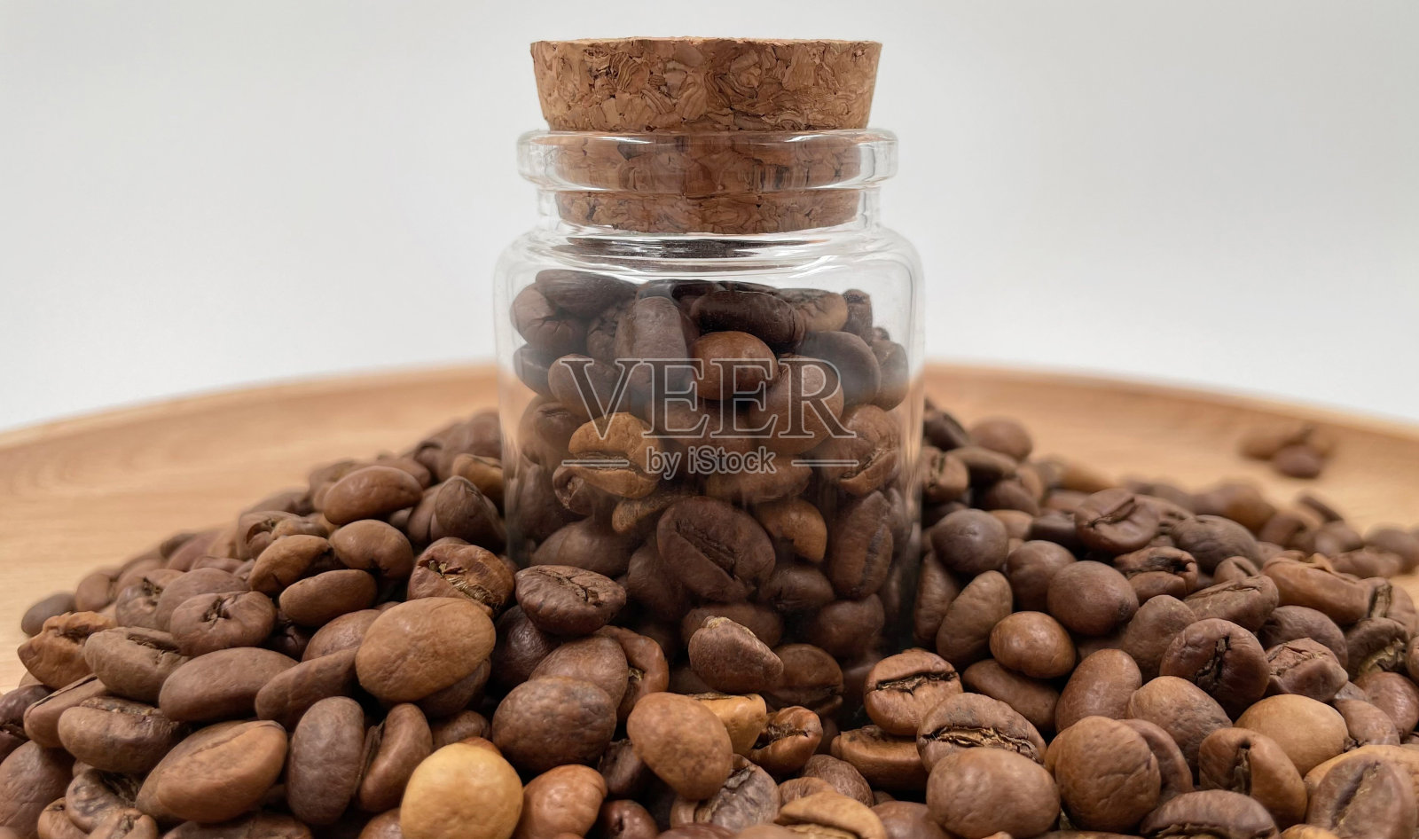 咖啡豆装在一个小玻璃瓶里，用软木盖盖在桌子上。装在透明、密封的储存容器中的咖啡豆。玻璃罐里的咖啡籽。照片摄影图片