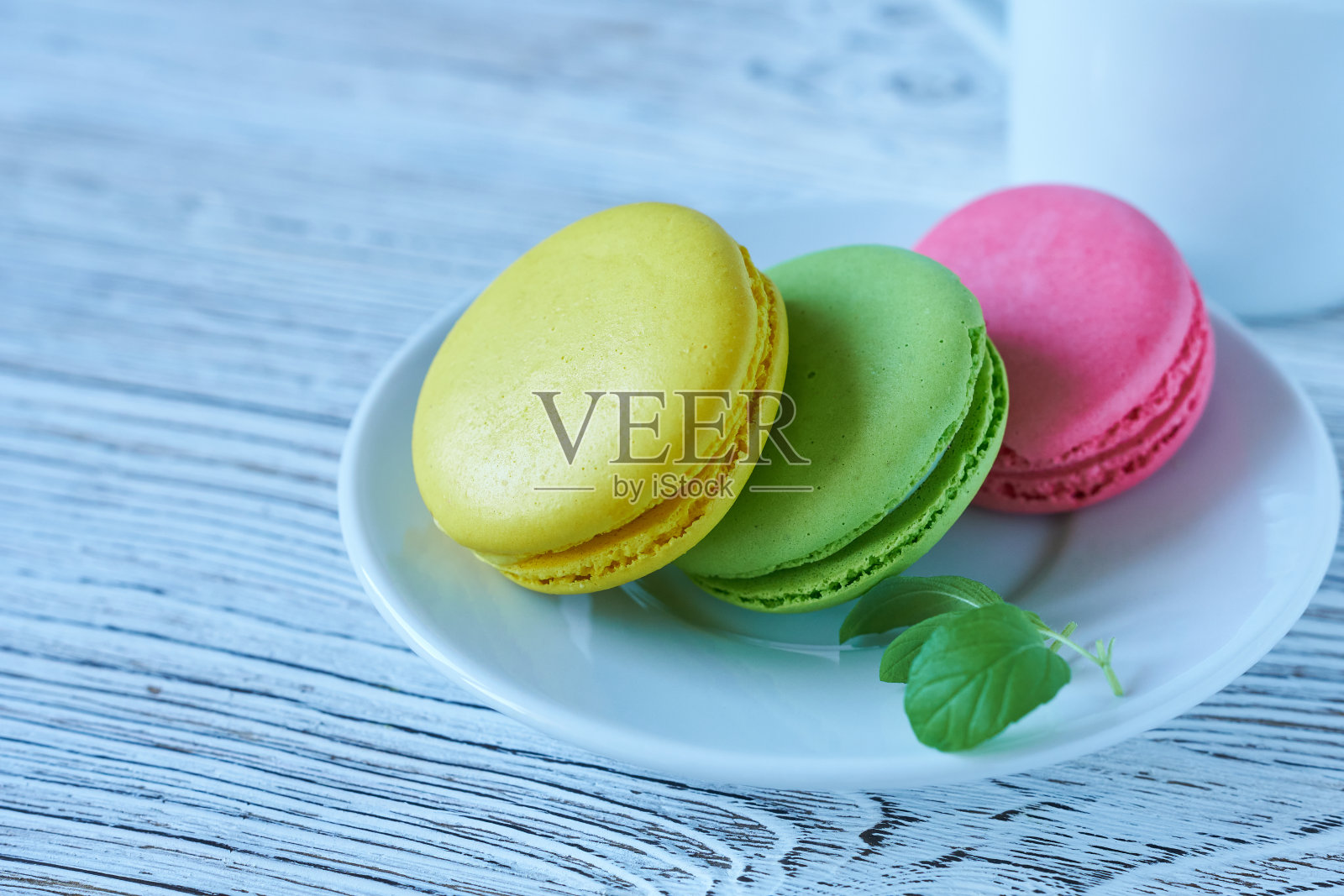 木制背景上的白色盘子上的彩色马卡龙照片摄影图片