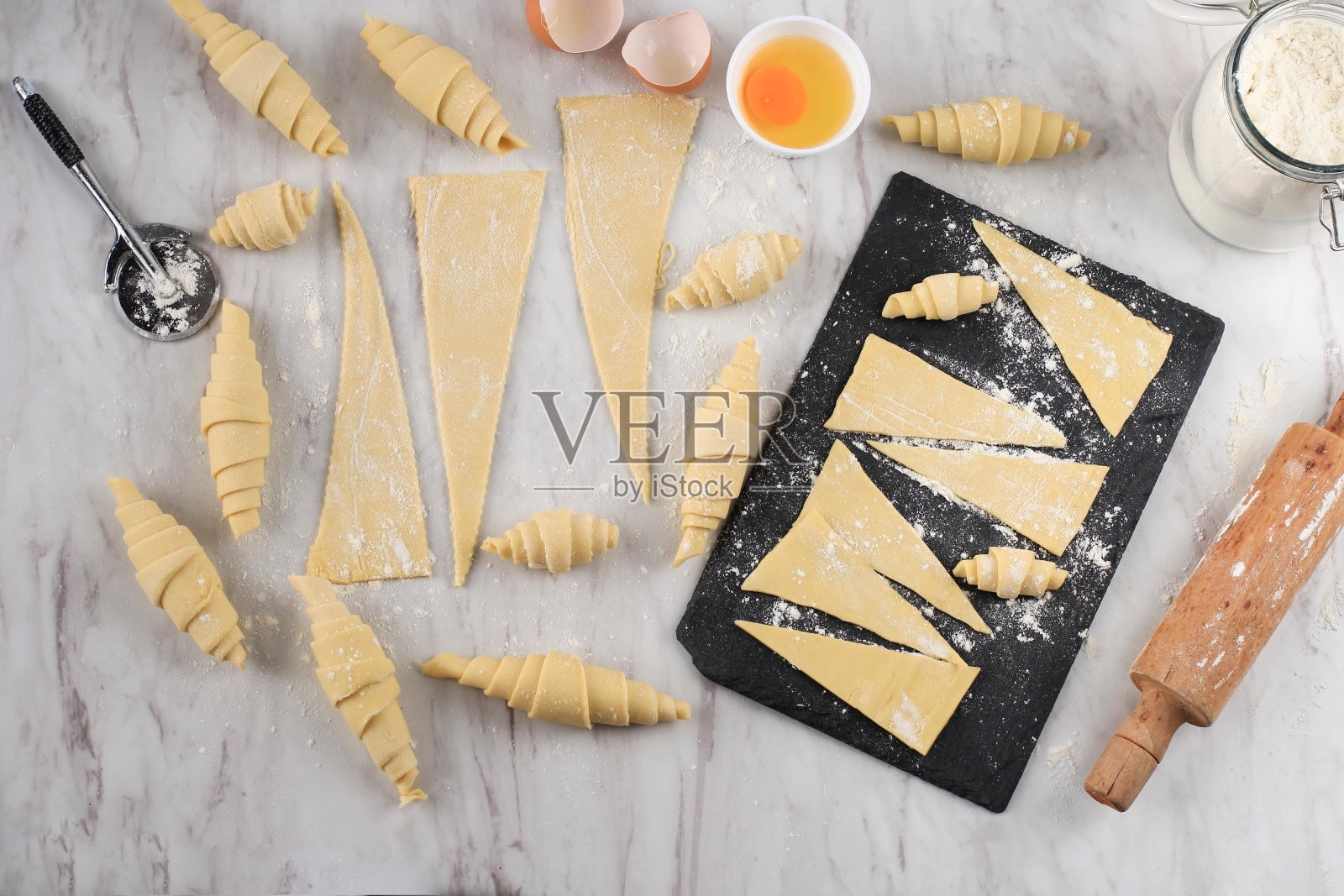 制作牛角包，白色大理石桌上的牛角包。厨房烘焙准备过程照片摄影图片