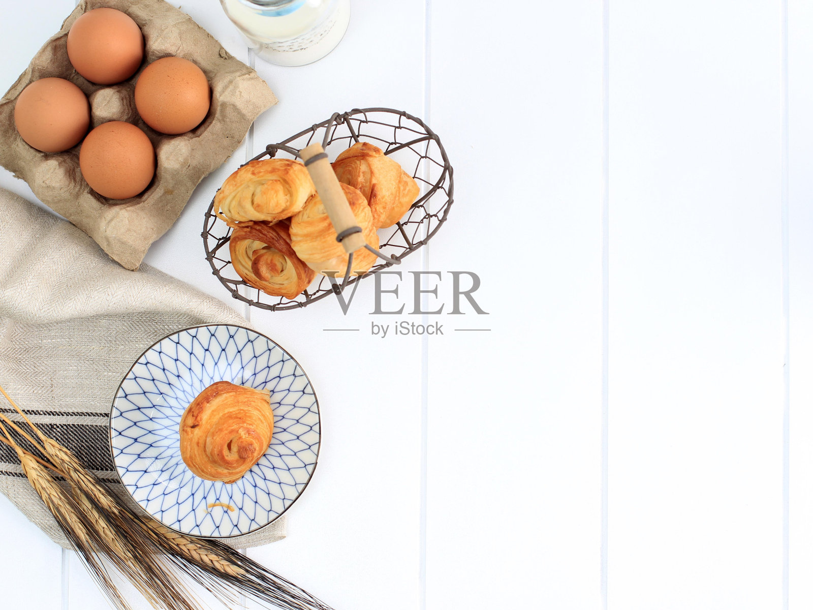 牛奶迷你牛角包，法式黄油酥皮。在白色厨房的盘子和编织的铁丝篮子。文本的复制空间。照片摄影图片