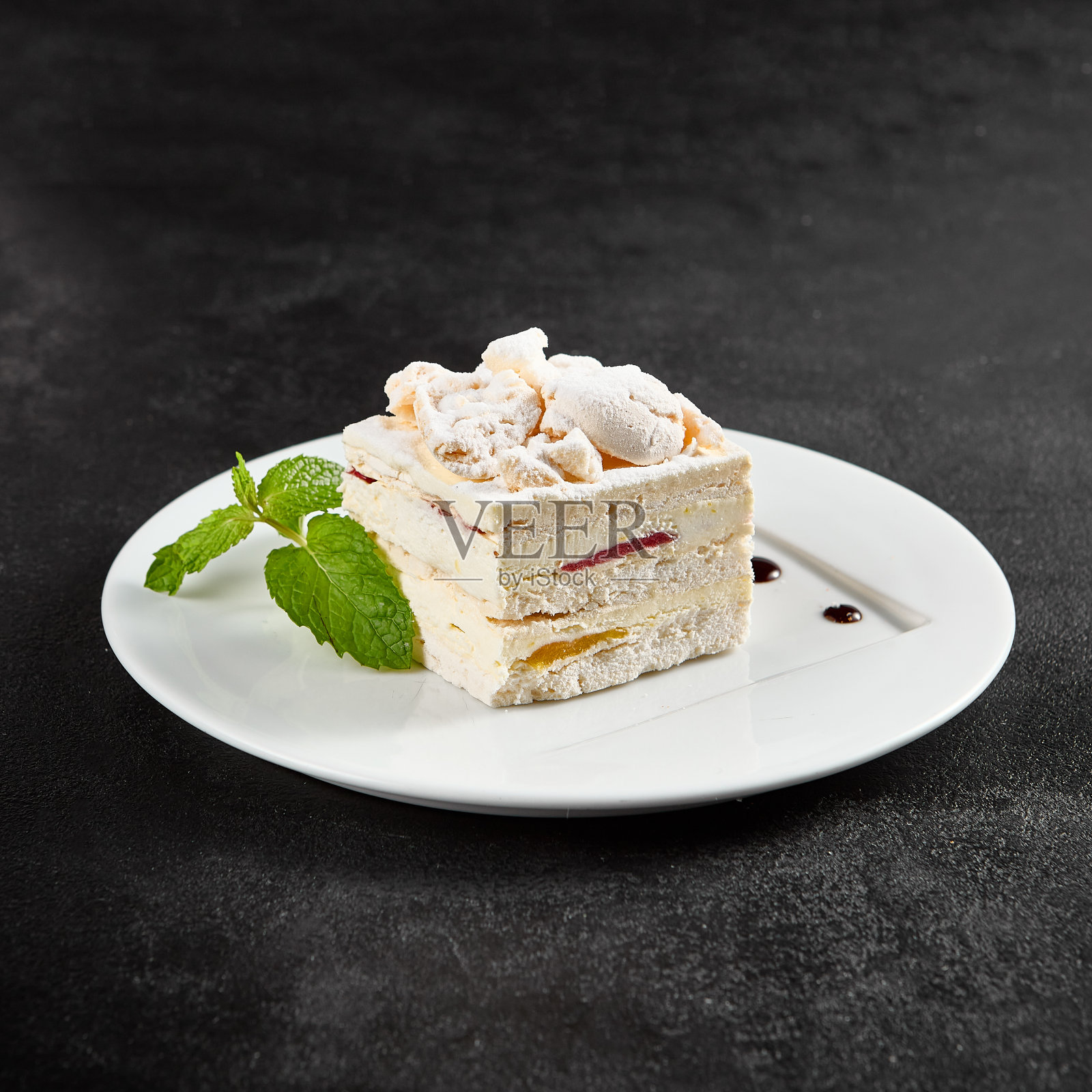 精致的蛋白酥饼，内馅是奶油芝士，白色盘子里点缀着一根薄荷照片摄影图片