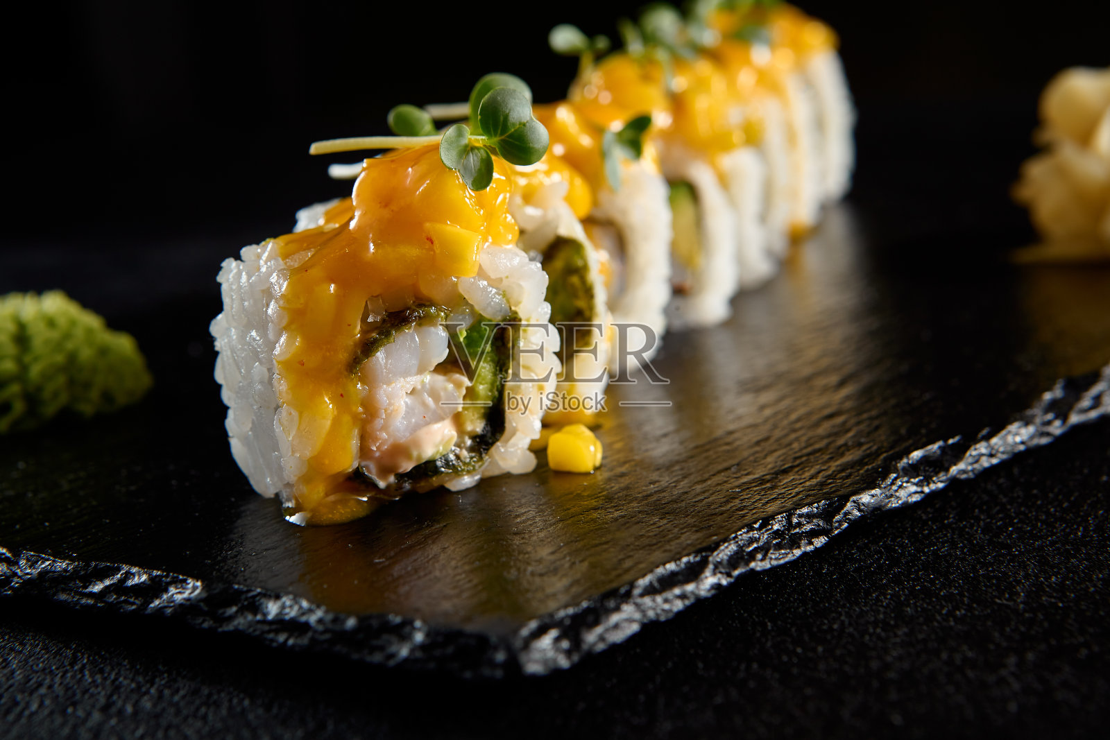 虾寿司卷配芒果塔塔，在黑色石板上提供奢华的展示照片摄影图片