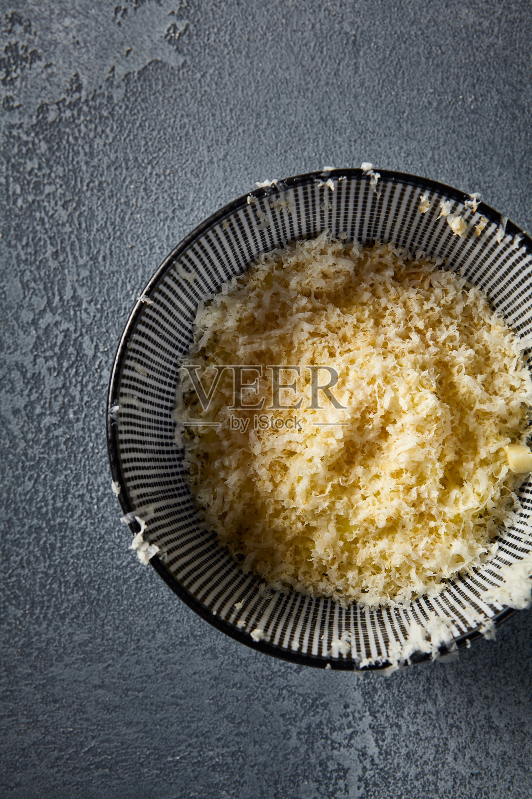 垂直向下的视角，强调了法式洋葱汤的层次感和质感。碗里融化的奶酪和洋葱块与灰色的背景形成了鲜明的对比照片摄影图片