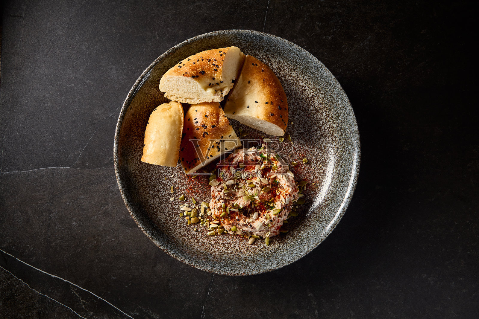 乌兹别克土门面包配上鹰嘴豆泥放在一个黑色的陶瓷盘子里，在一个黑色的极简主义背景上体现了东方烹饪的乐趣照片摄影图片