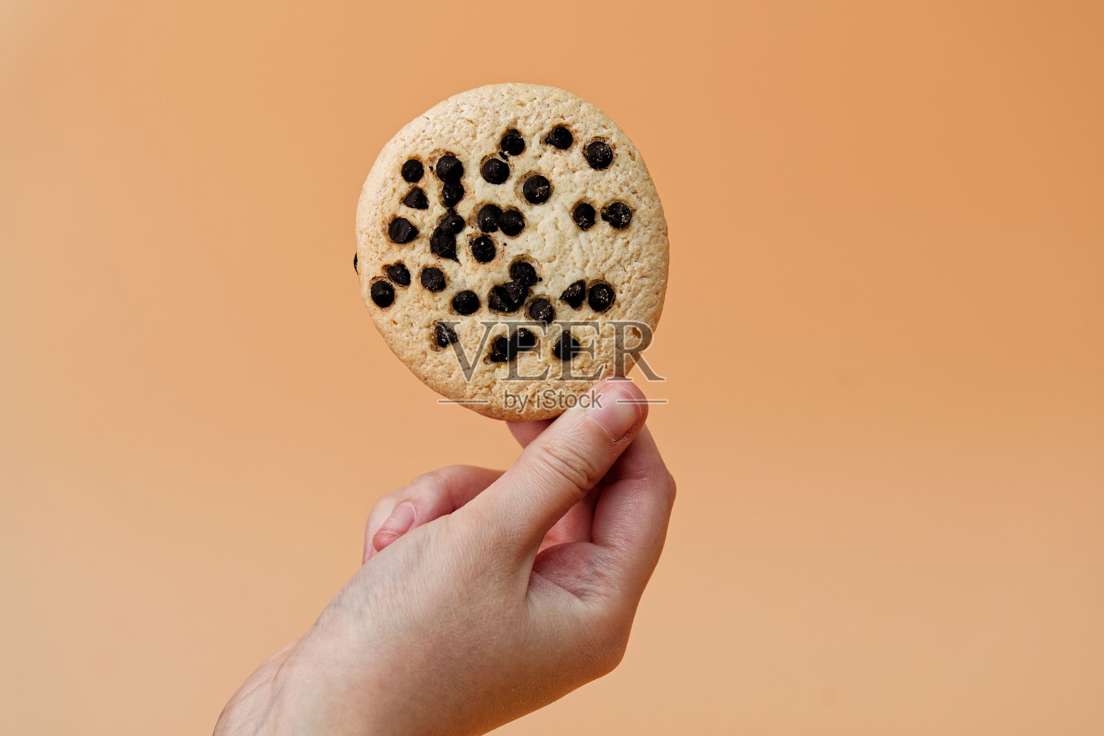 无法辨认的人(手在相框里)拿着巧克力饼干。工作室的照片照片摄影图片