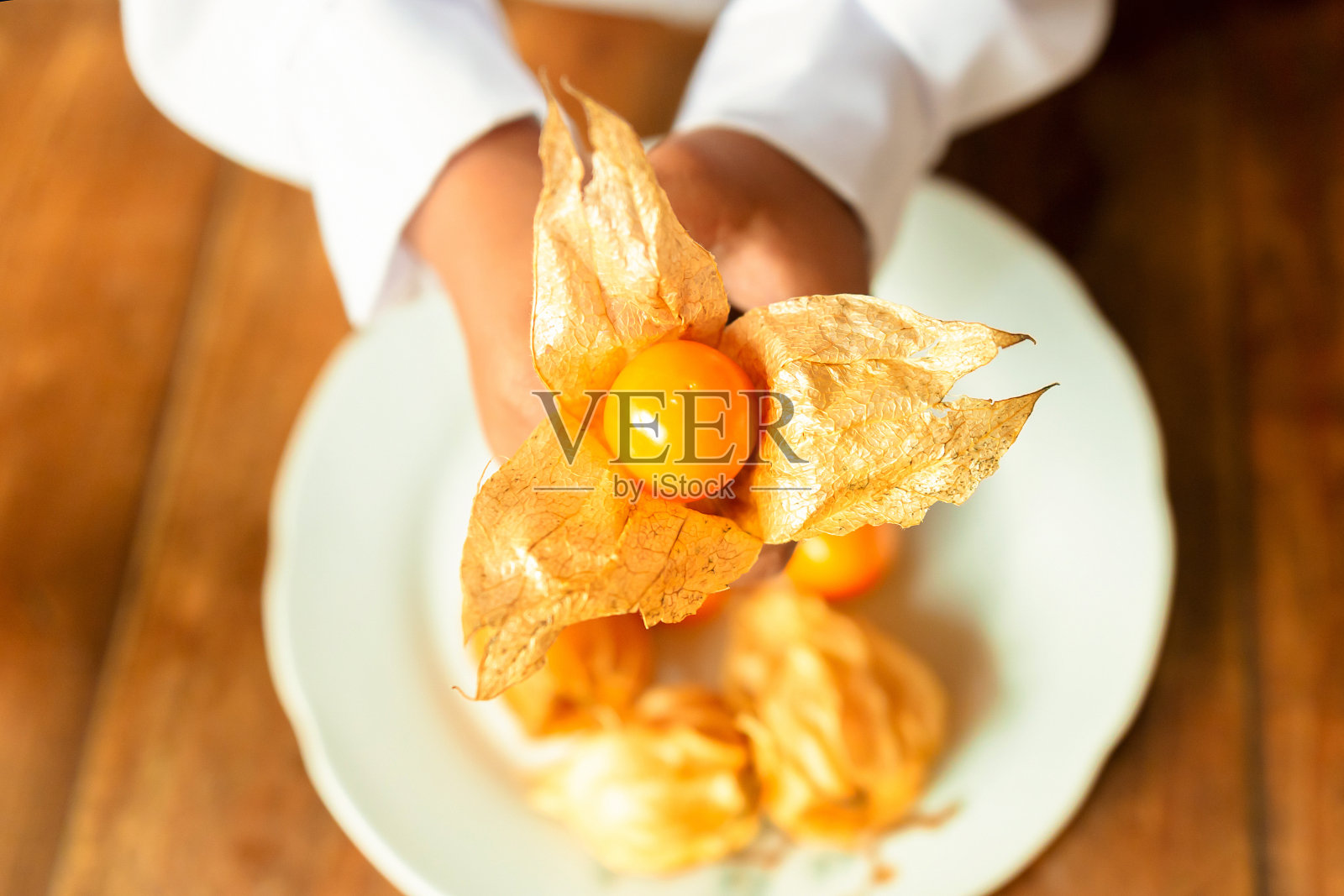 小女孩打开并吃着Capulí或Aguaymanto水果。照片摄影图片