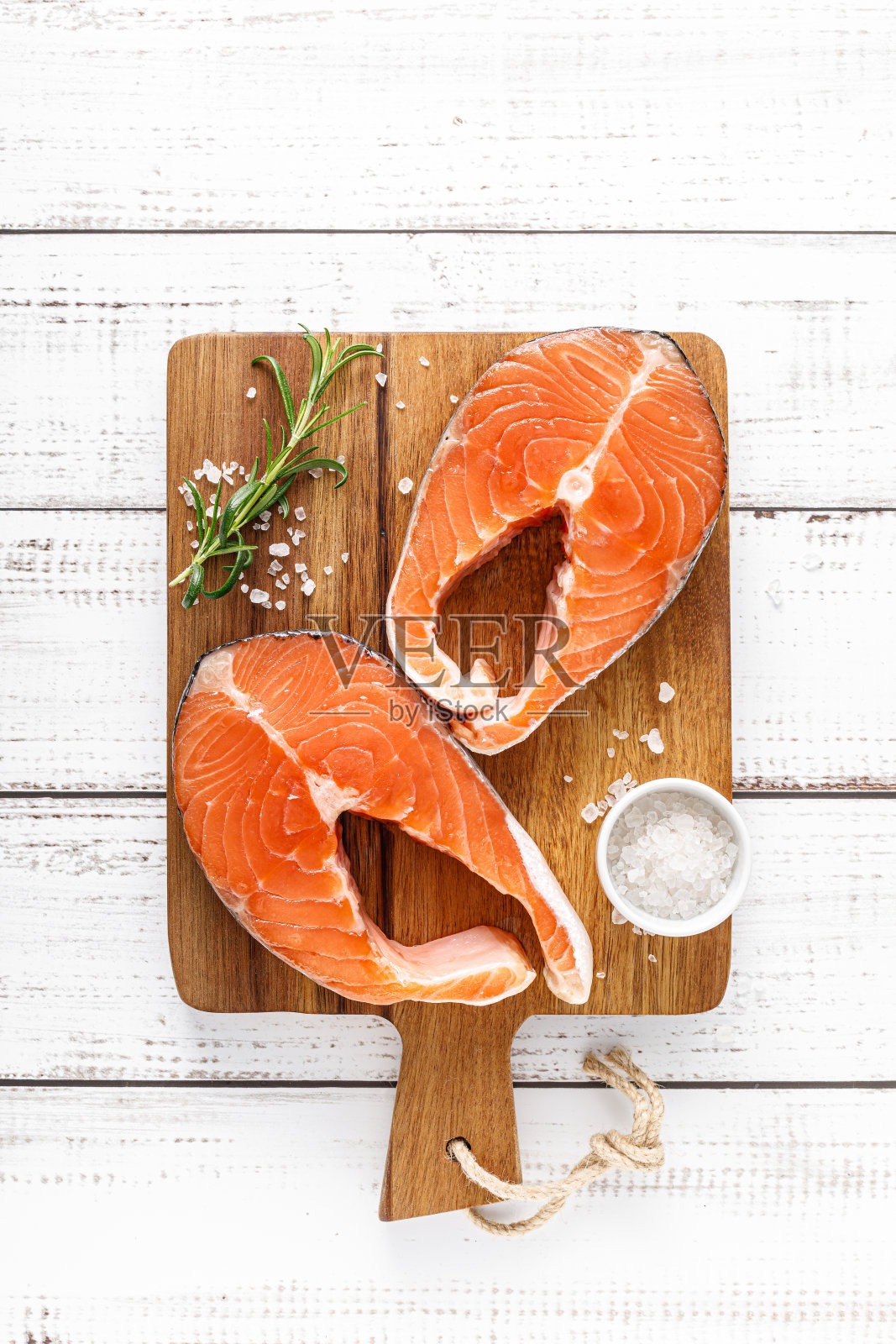 新鲜的生鲑鱼排和烹饪材料放在一块板上，俯视图照片摄影图片