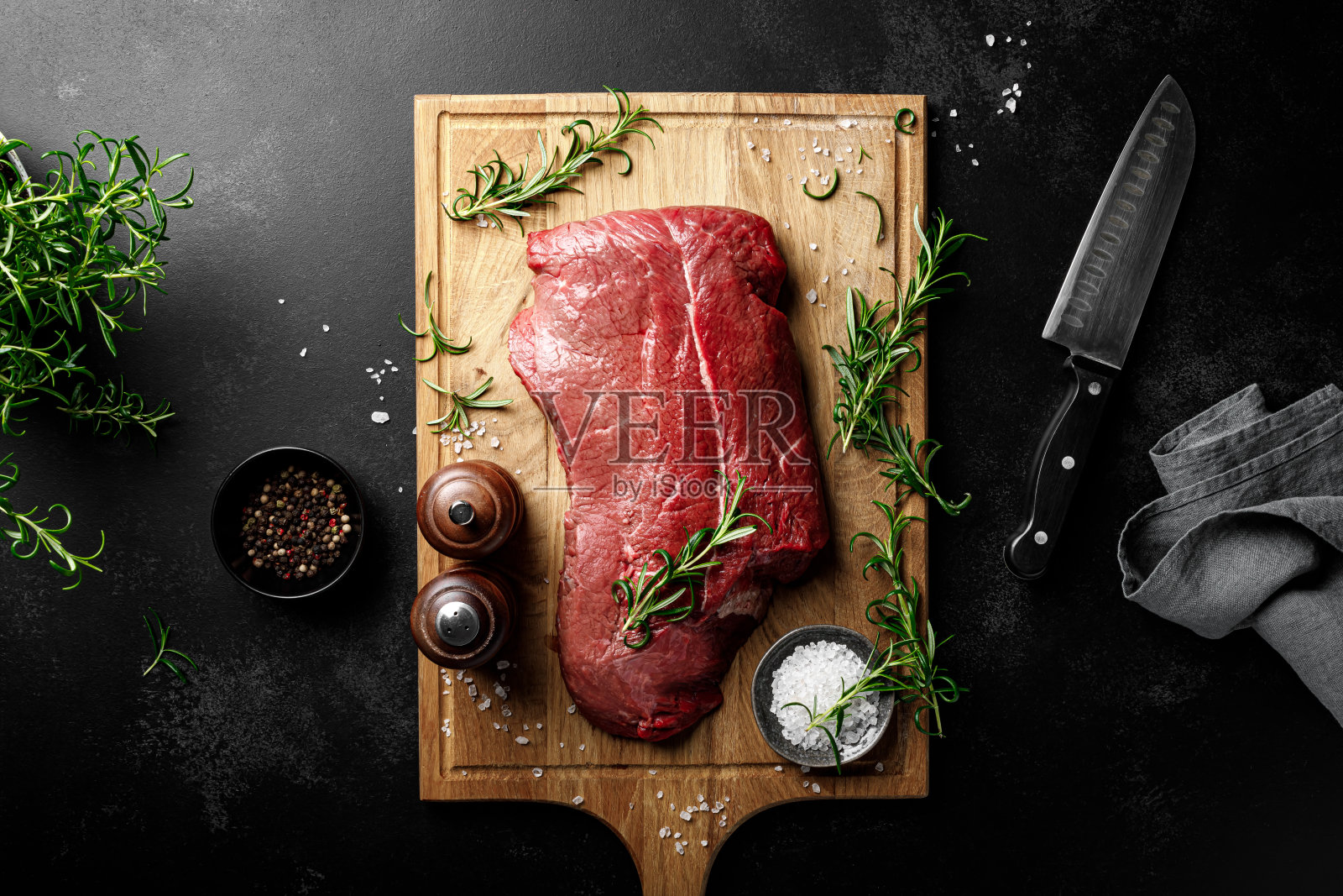 切菜板上的牛肉主菜，黑色背景上的生牛肉片，俯视图照片摄影图片