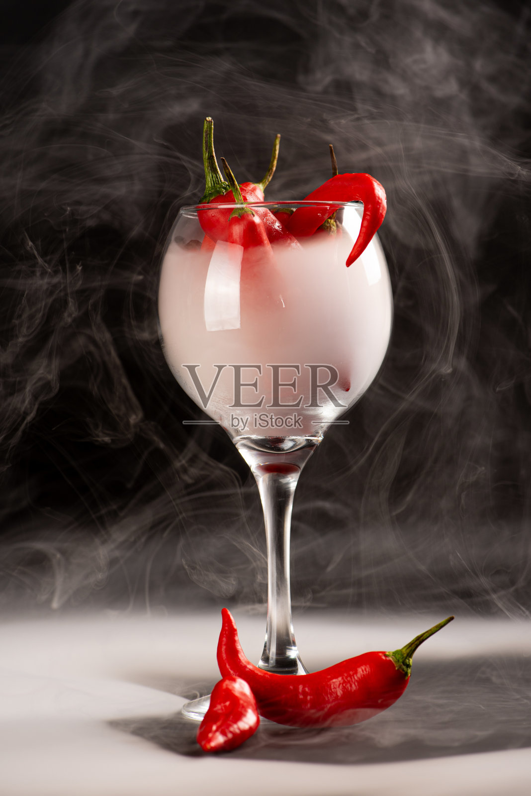 辣椒，美丽的红辣椒在一个杯子内详细与烟，黑色背景，选择性聚焦。照片摄影图片