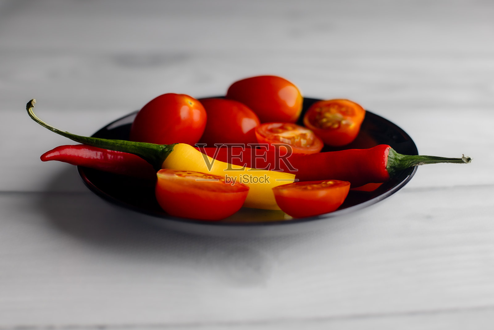 一个半辣椒放在黑色圆盘子里。照片摄影图片