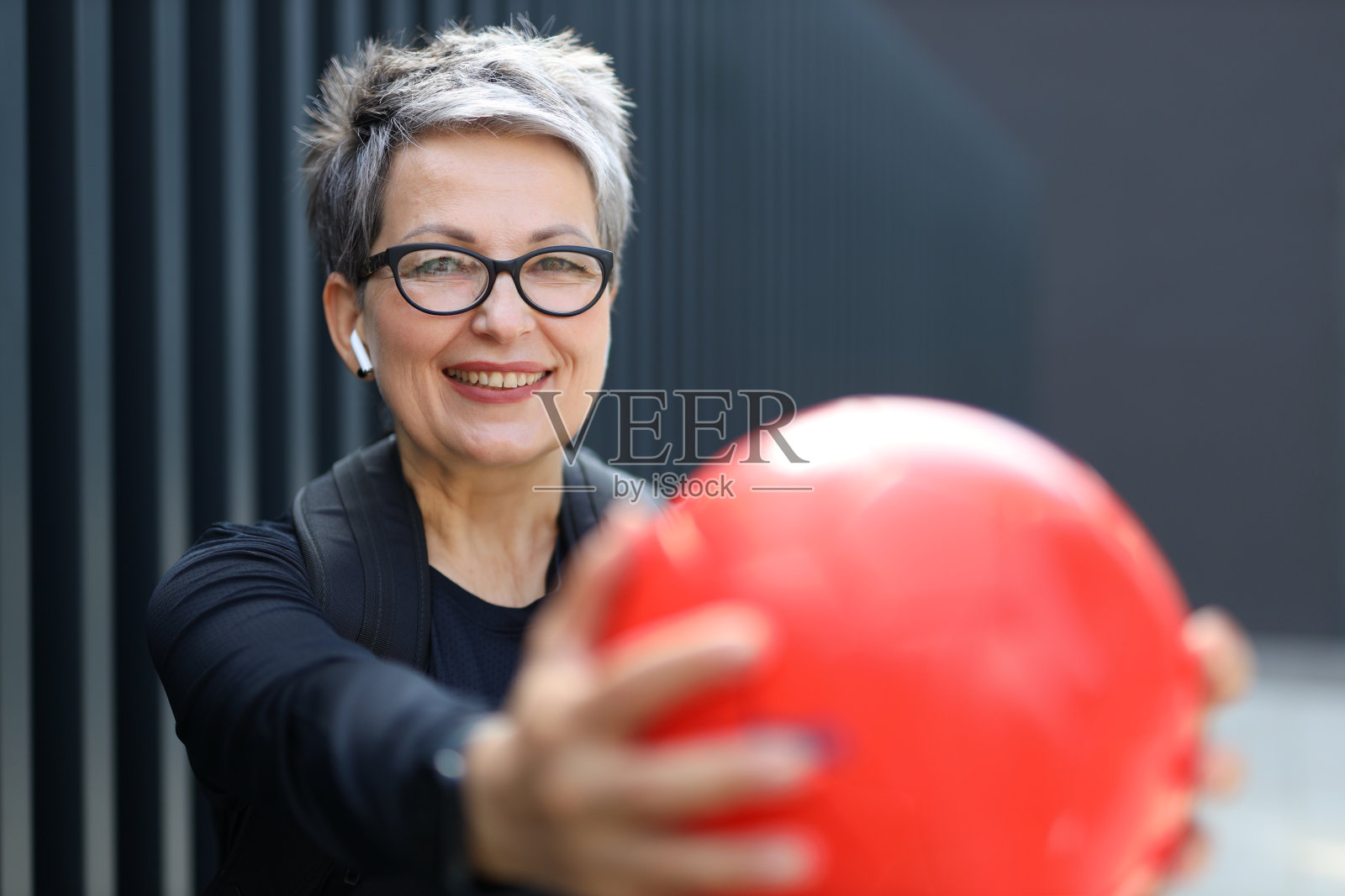 一位年长的白人妇女拿着球在户外享受夏天的游戏。照片摄影图片