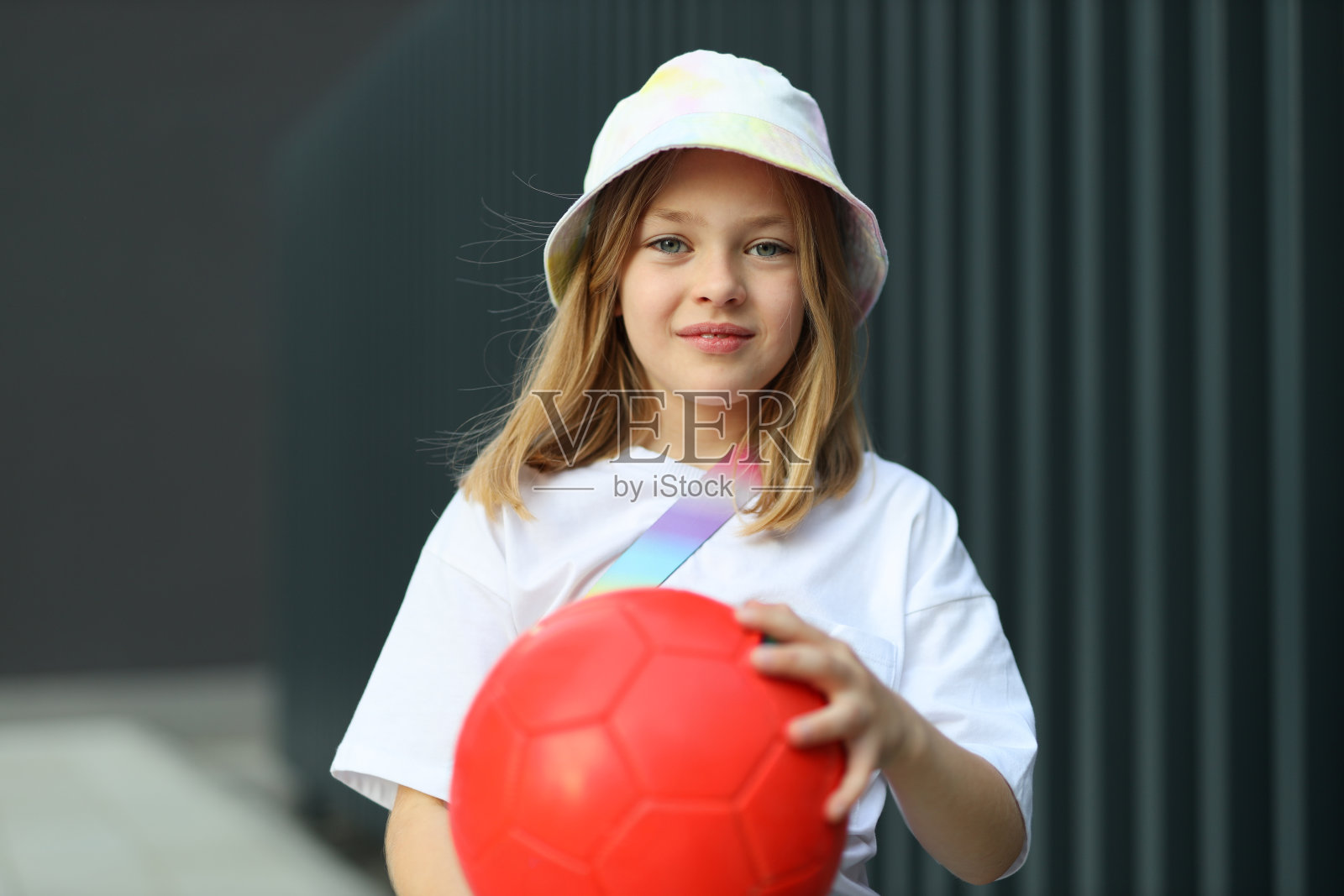 在一个阳光明媚的夏日，一个小女孩喜欢在户外踢足球，开心地笑着。照片摄影图片