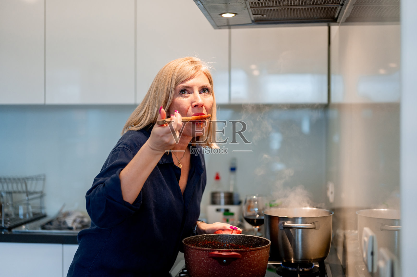 女人一边做饭一边品尝食物照片摄影图片