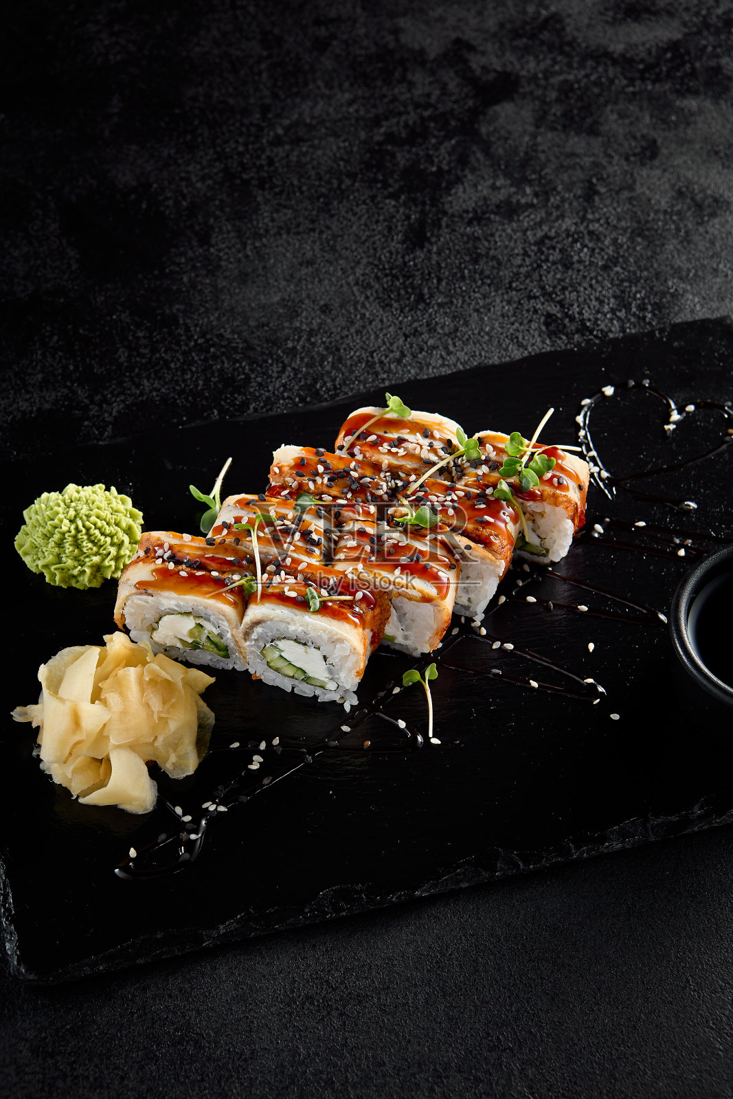 加拿大卷配鳗鱼和鲣鱼酱，与酱油和芥末一起放在黑石板上照片摄影图片