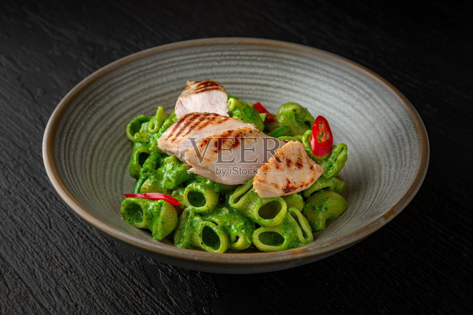 奶油意大利面，菠菜和火鸡在一个陶瓷盘子在深色纹理的背景。餐厅的菜单照片摄影图片