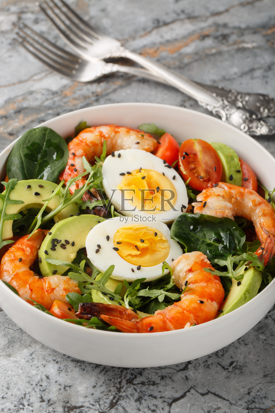 用虎虾、鳄梨、芝麻菜、菠菜、西红柿和芝麻做成的减肥沙拉。垂直照片摄影图片