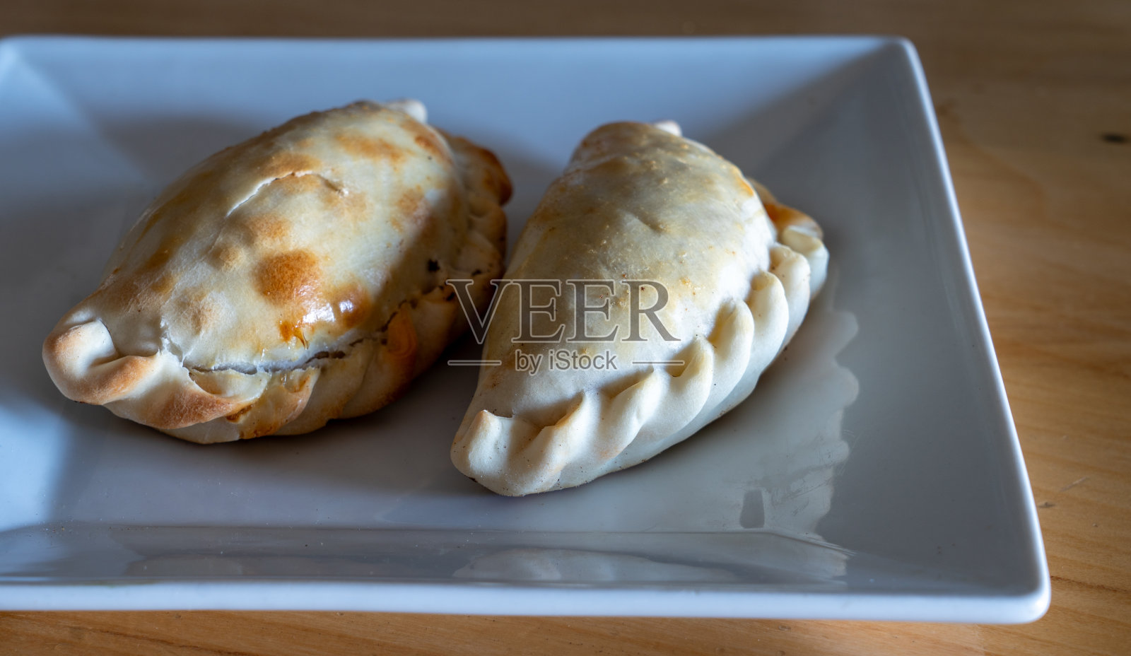 两个肉馅卷饼装在白色方形盘子里照片摄影图片